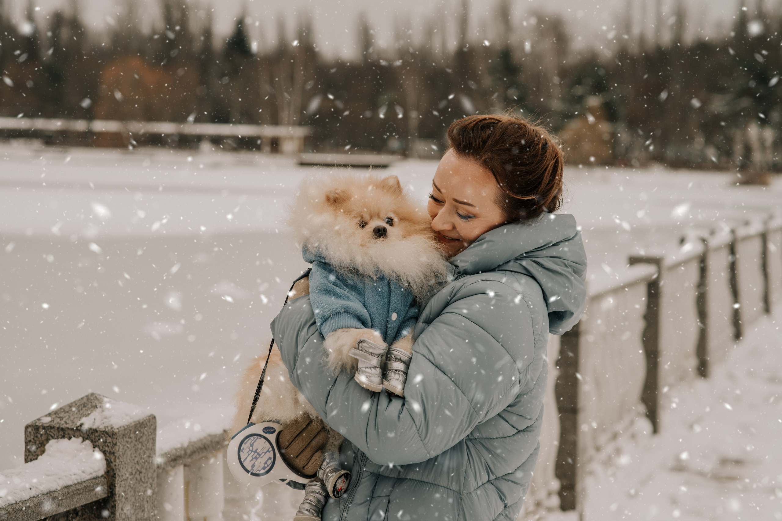 Фотосессия с собакой шпицем в зимнем парке девушки в голубом пуховике