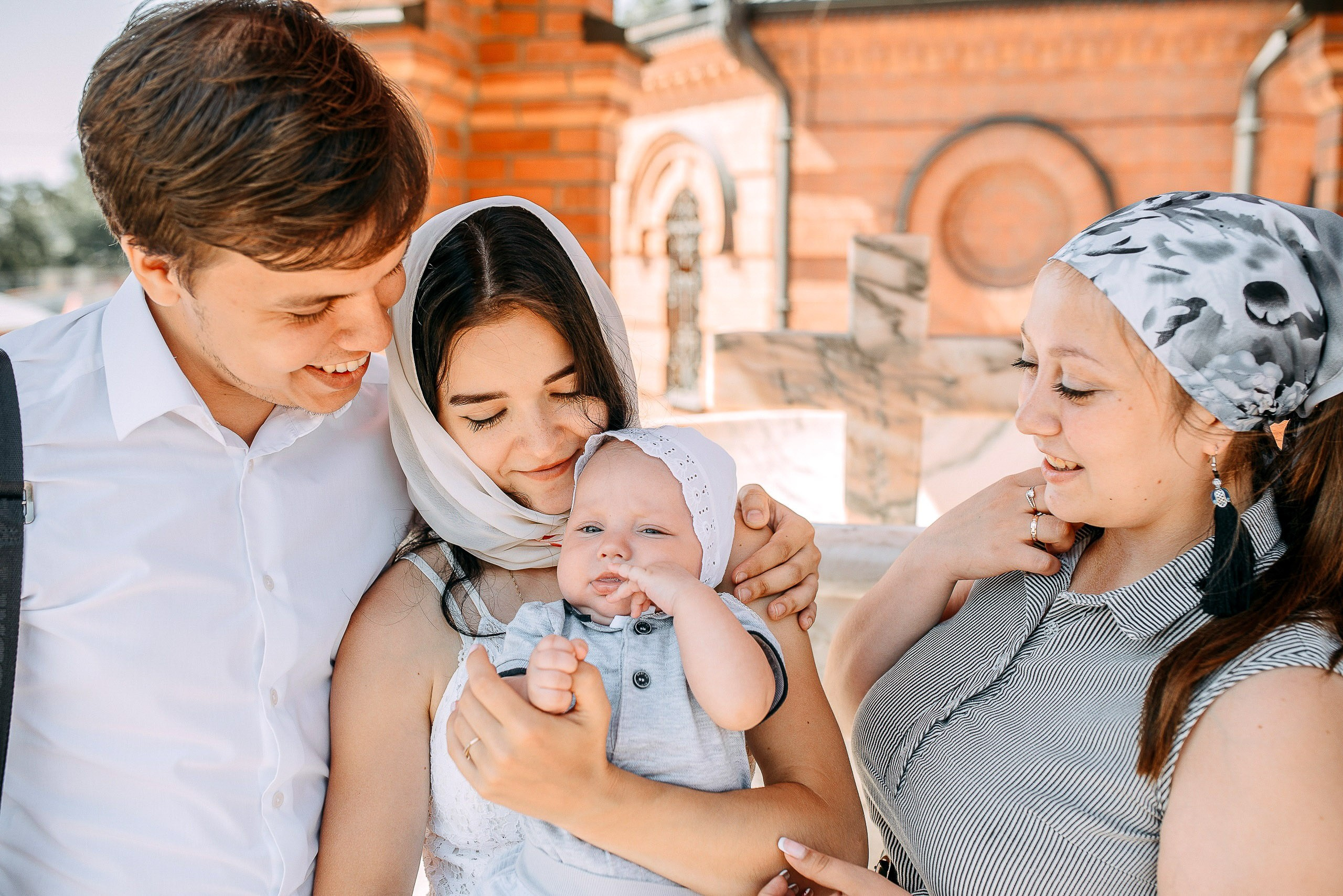 Фотограф на крещение в Новосибирске, семейный портрет родителей с младенцем у храма.