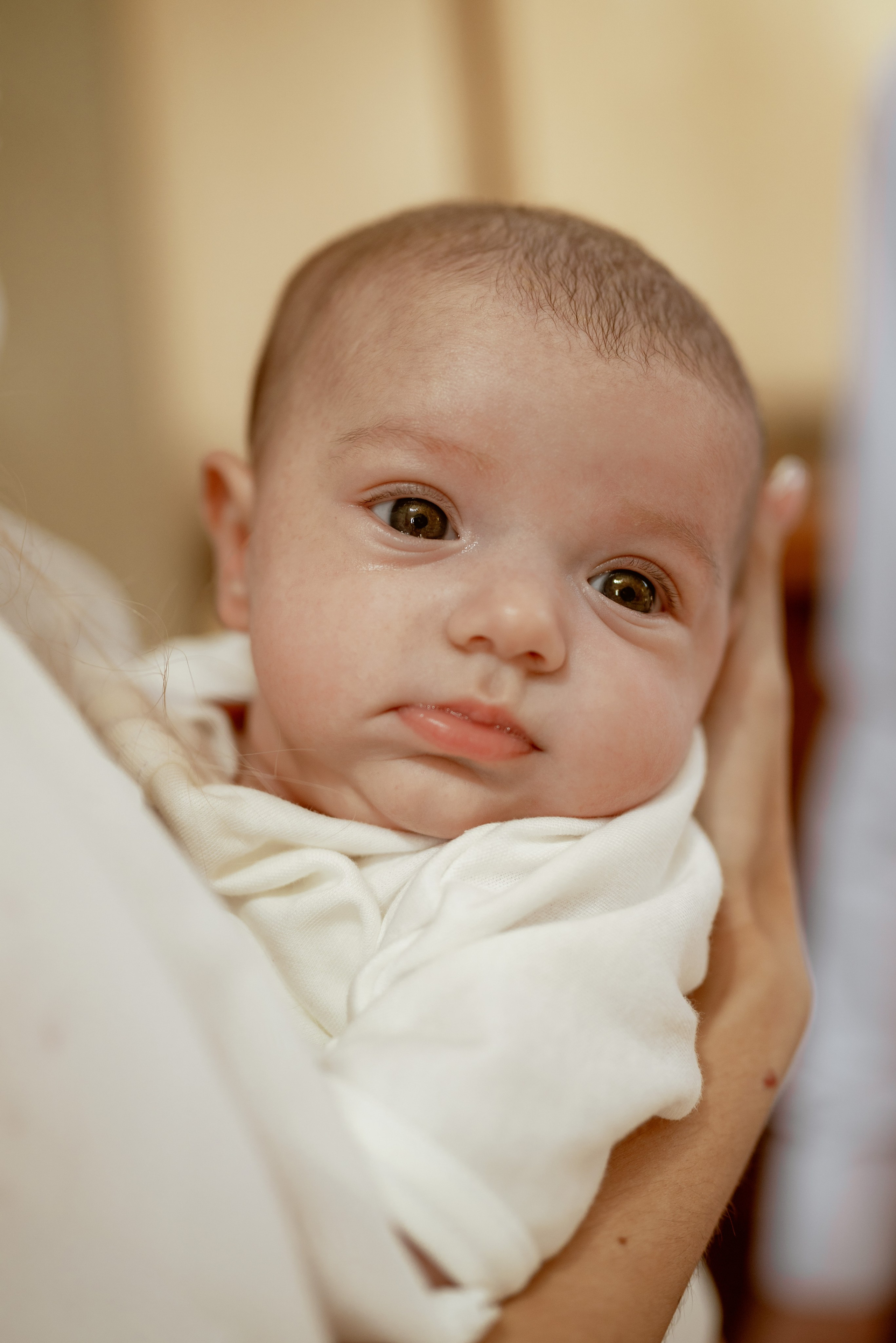 Малыш на руках у мамы во время крещения