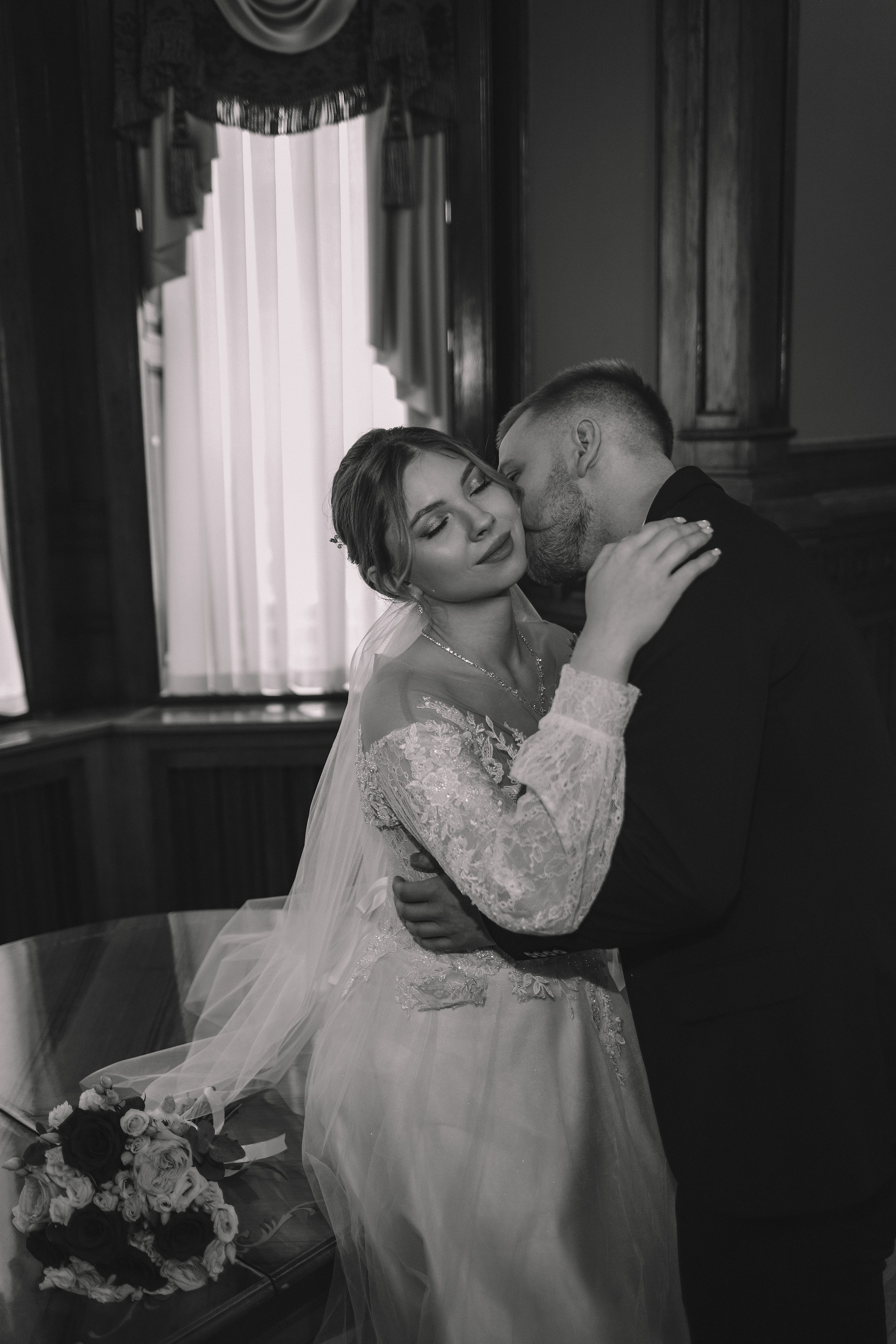 Пара обнимается в интерьере ЗАГСа, тёплый свет