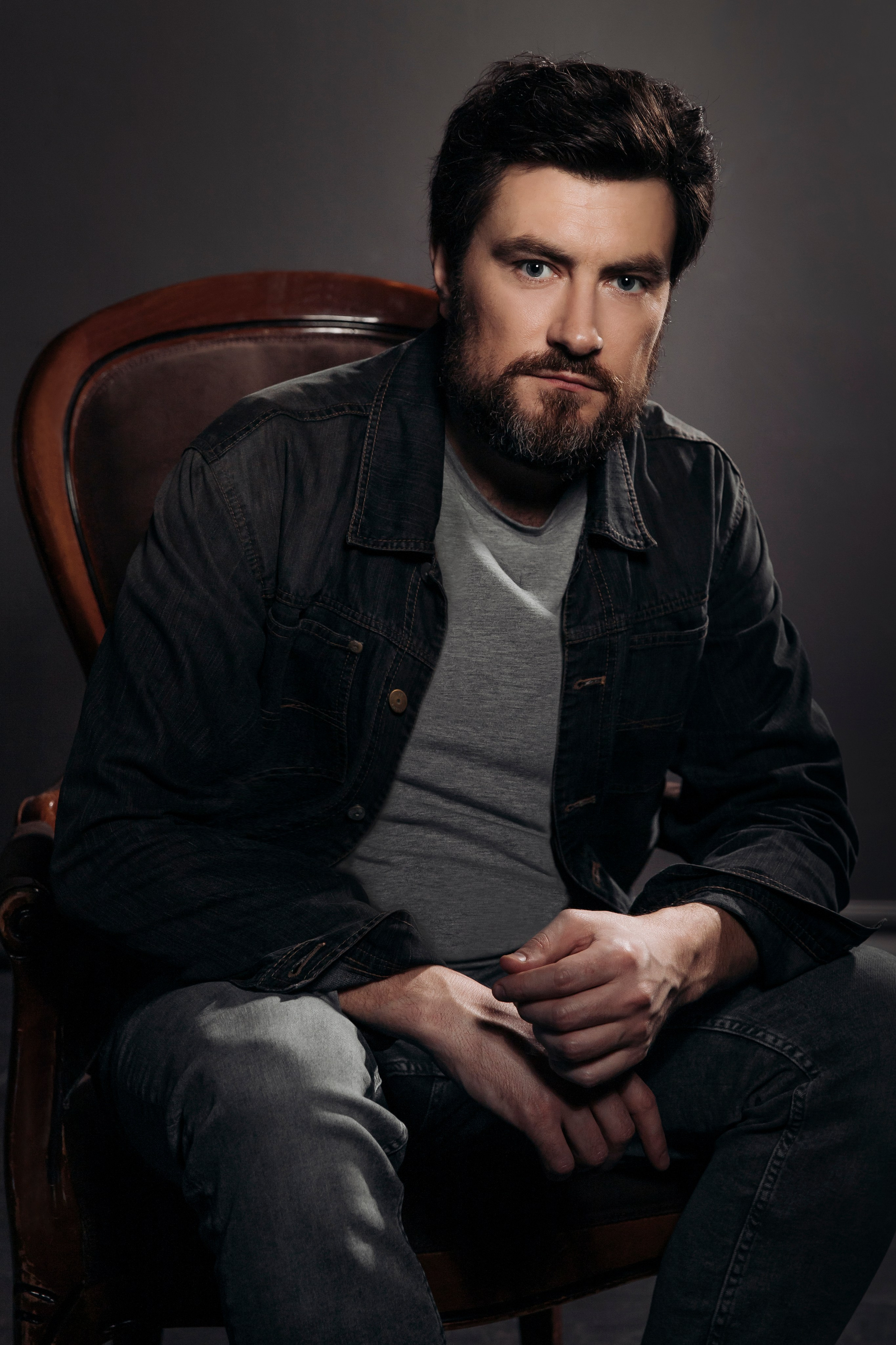 Мужчина с бородой сидит в кресле