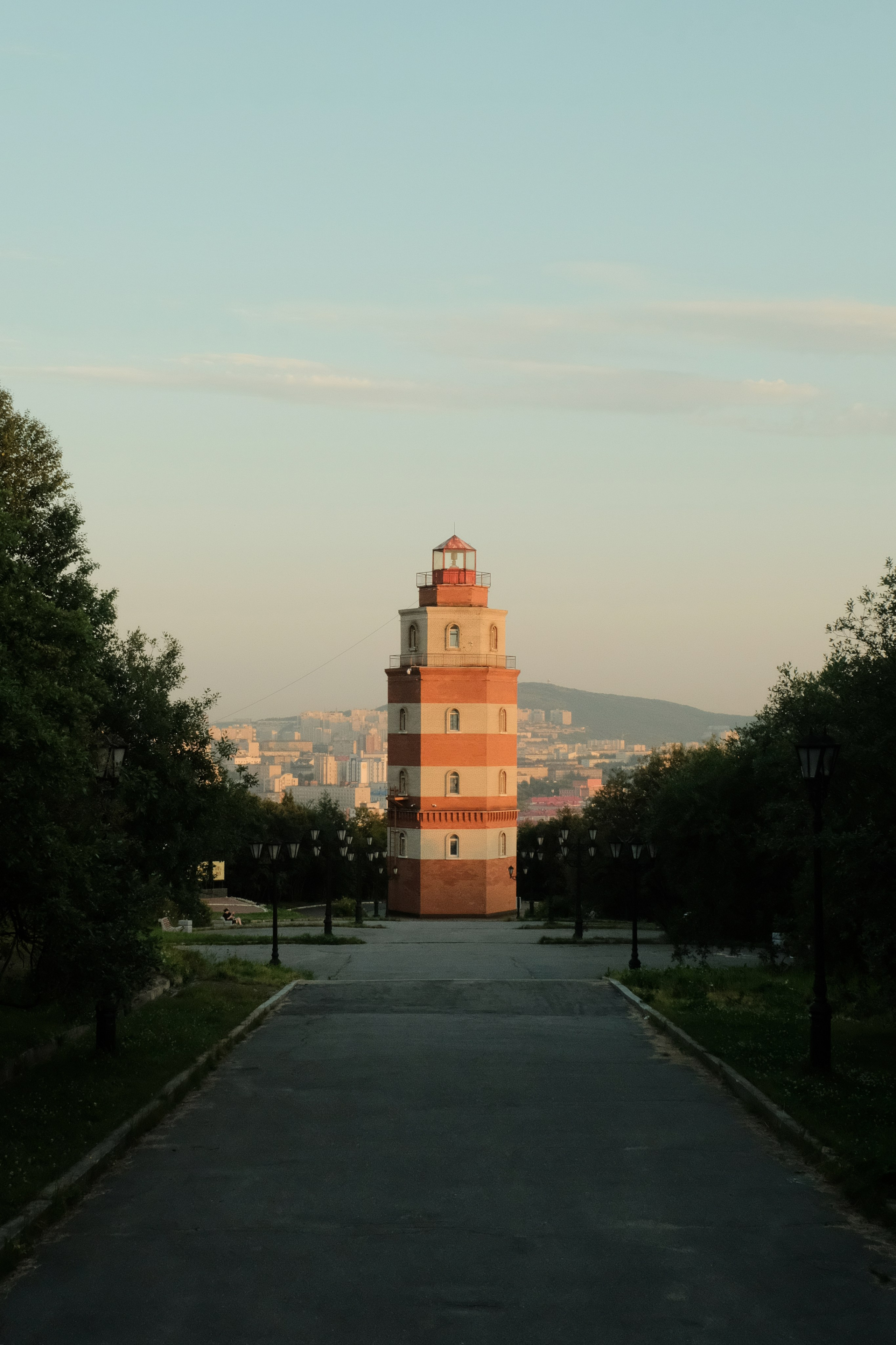 In the center of the location is an old lighthouse that does not work on a hill above the city during the polar day in Murmansk.