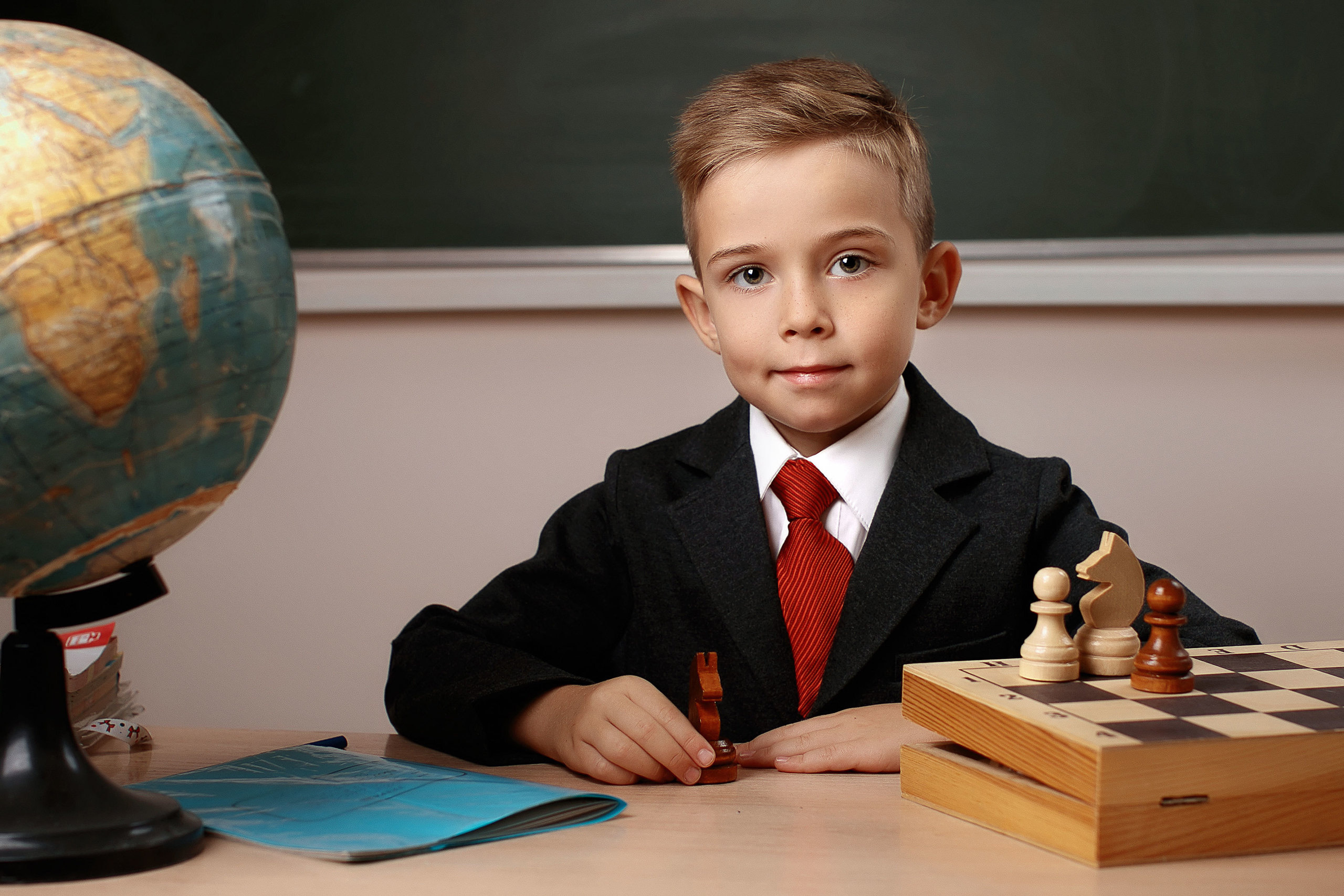 портрет школьника за партой с глобусом