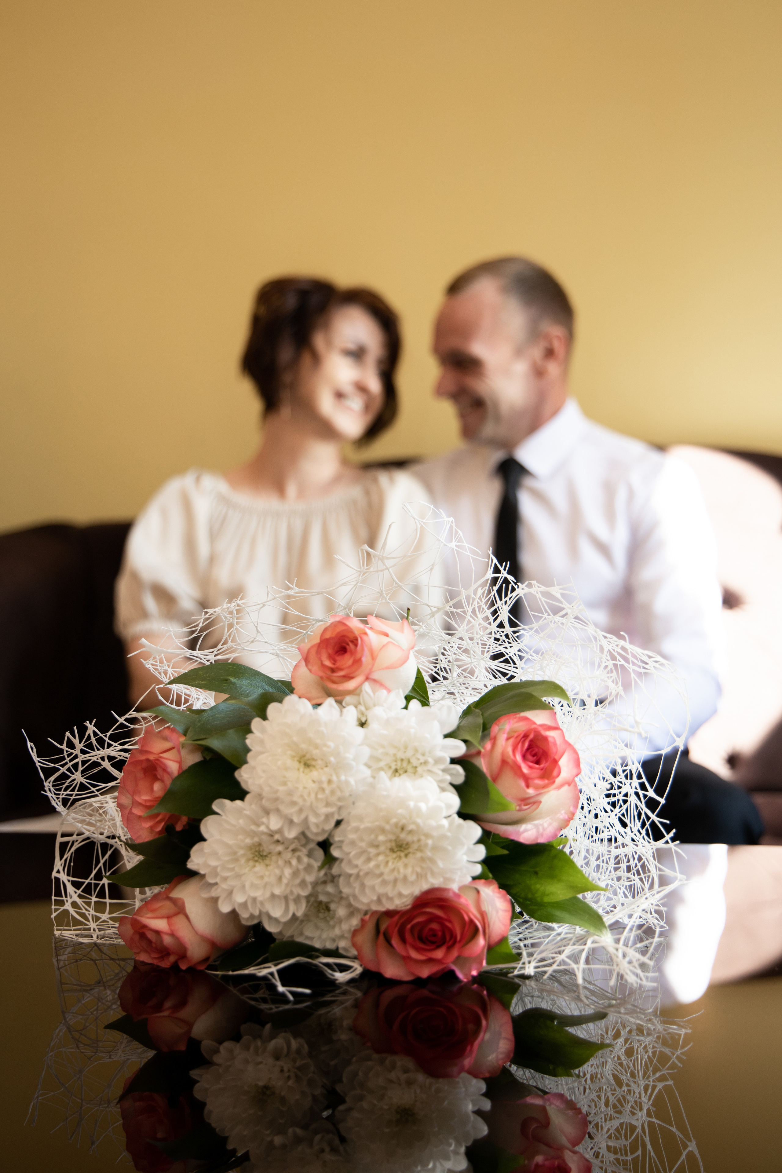 Молодожены сидят на диване, на переднем плане букет невесты. Свадебная фотосессия Астрахань.