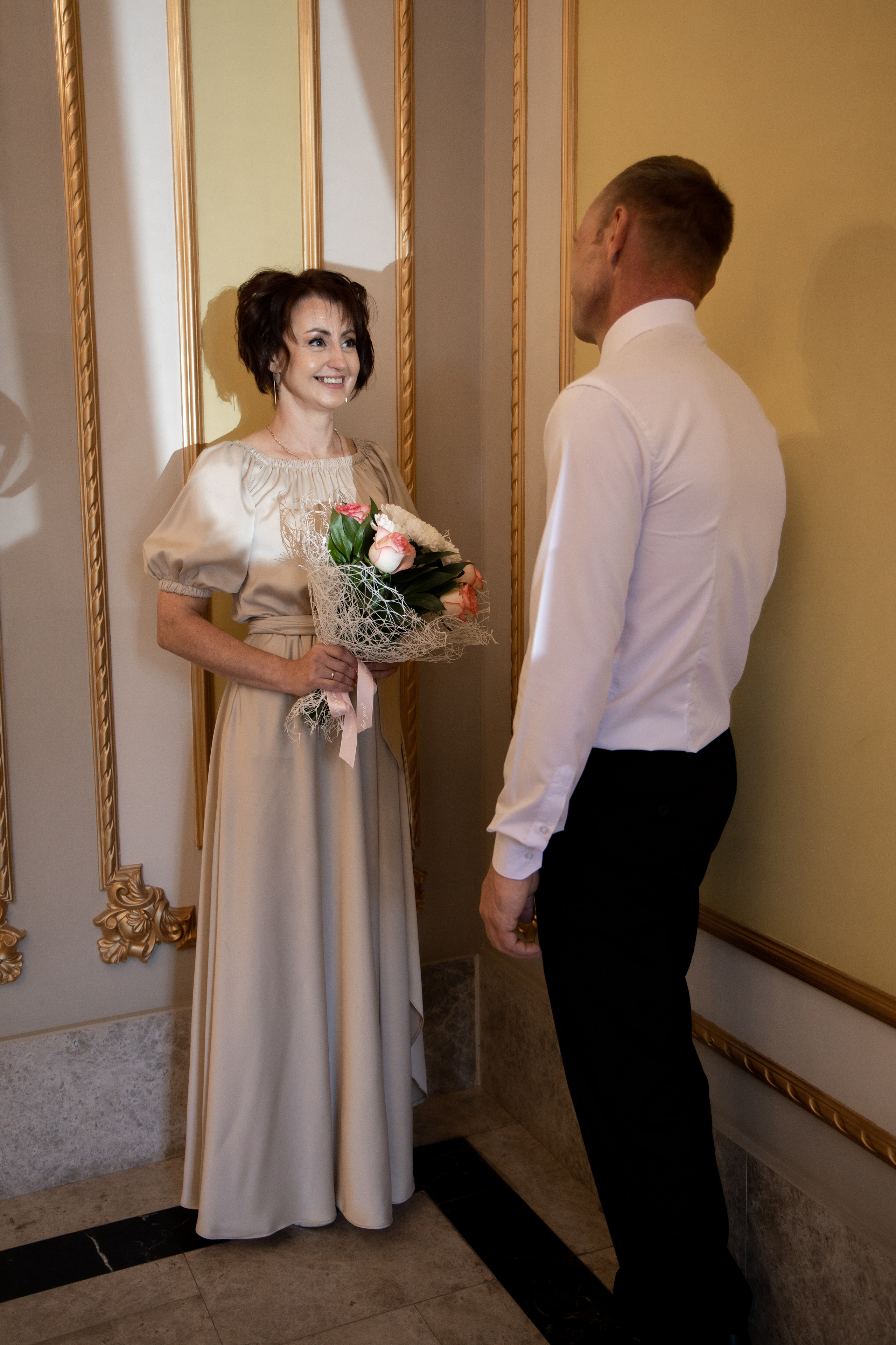 Жених и невеста в полный рост, невеста смотрит на жениха, в руках букет. Жених стоит спиной к камере. Свадебная фотосессия Астрахань.