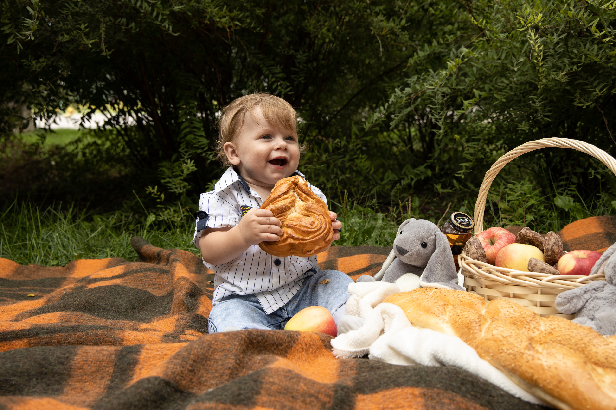 Малыш сидит на пледе, в руках держит булку. Детская съёмка Астрахань.