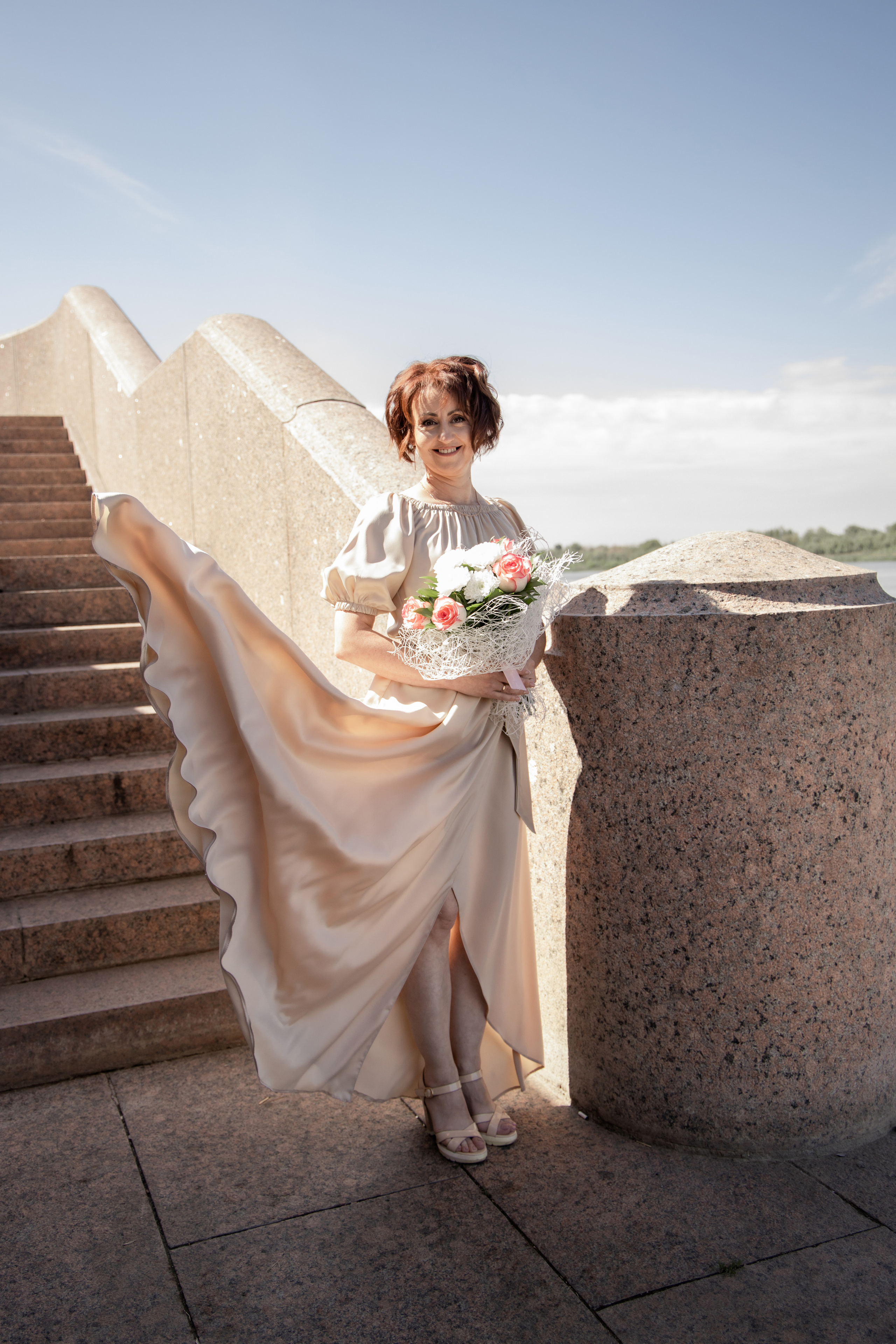 Невеста стоит в лёгком бежевом платье, юбка платья развивается. Свадебная фотосессия Астрахань.