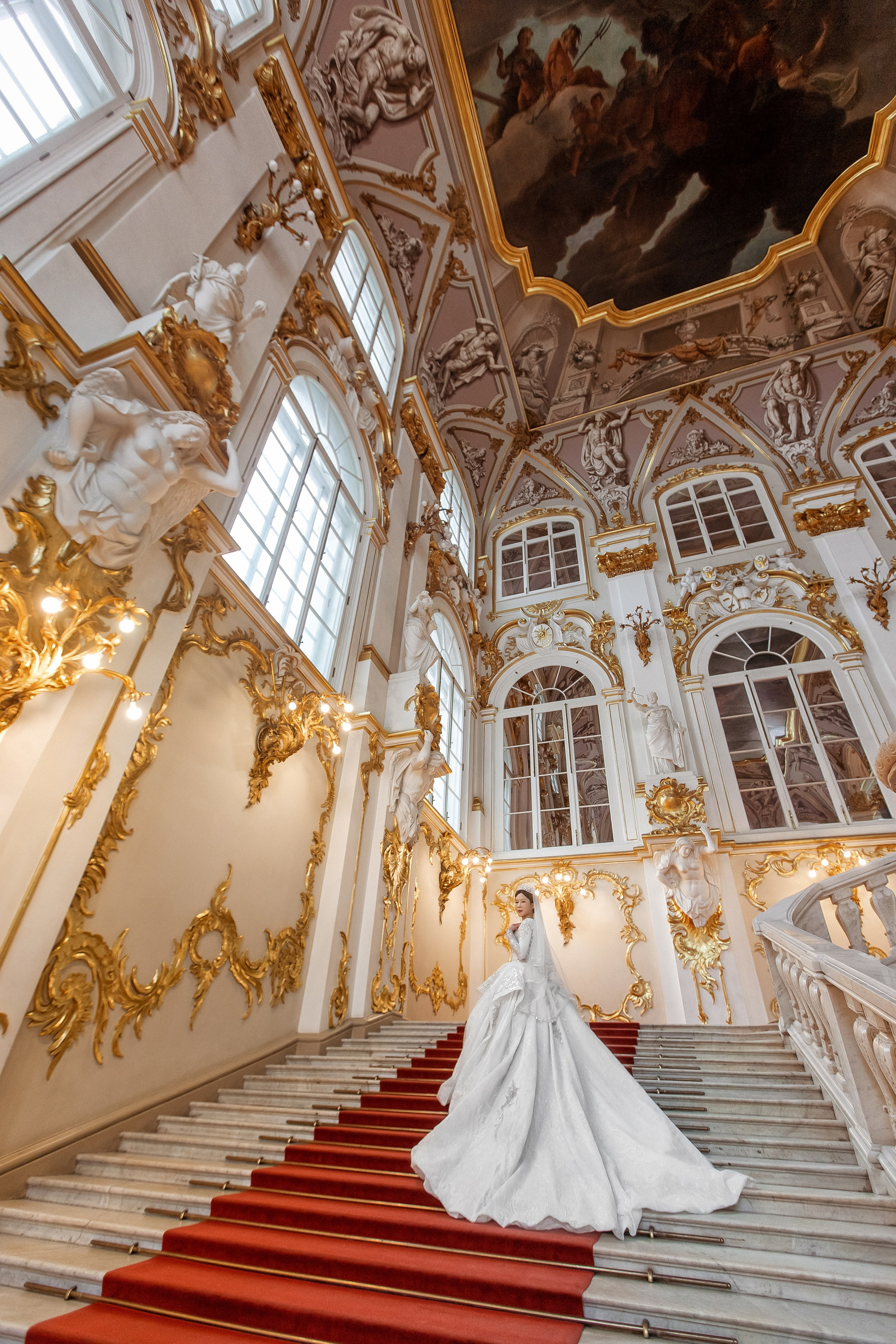 Невеста в свадебном платье с длинным шлейфом на лестнице в Эрмитаже.