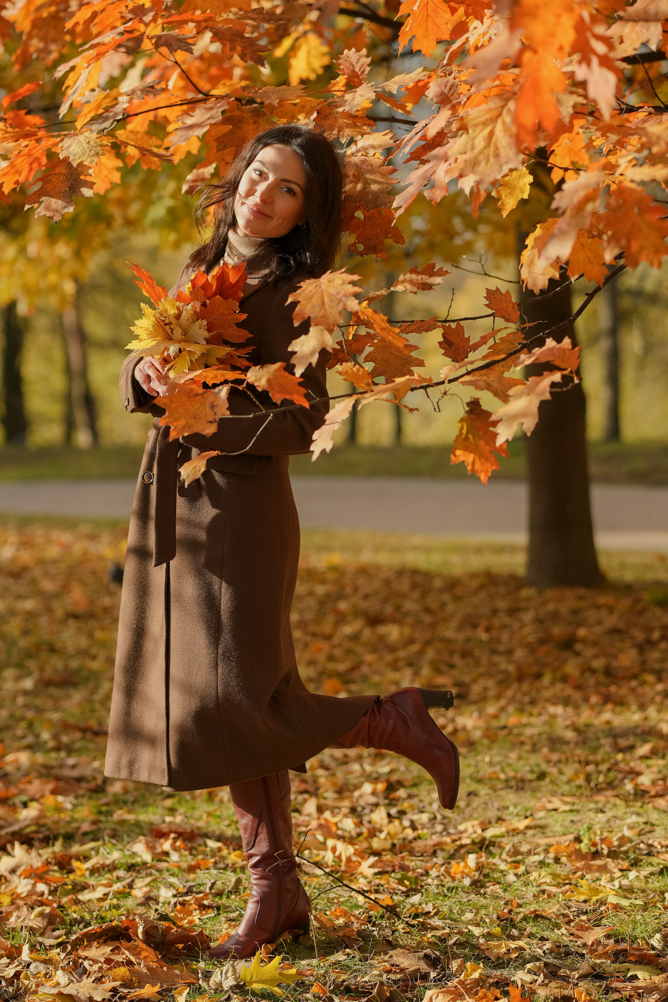 Красивая девушка брюнетка в парке золотой осенью в красных дубовых листьях