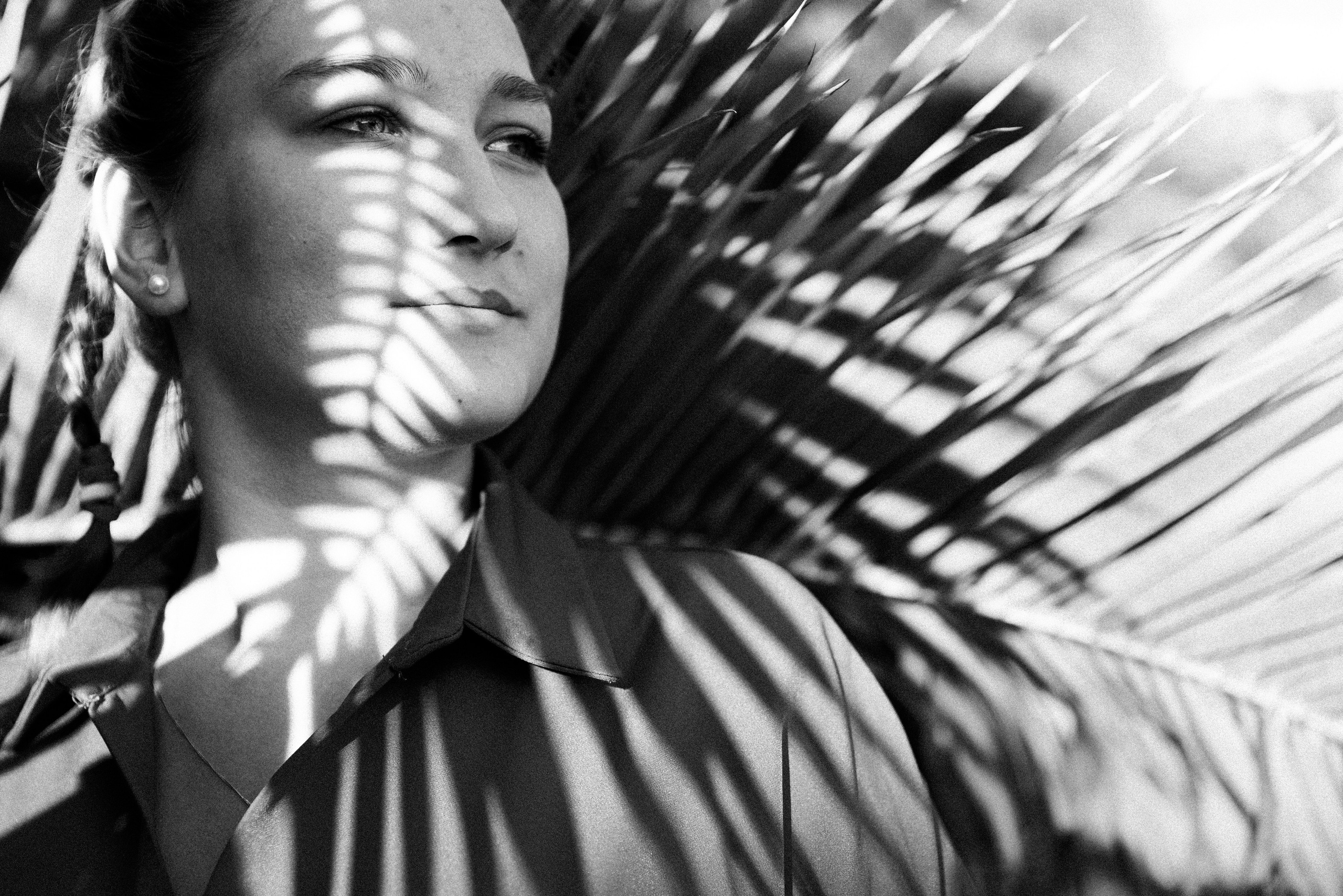 Интересная полосатая тень от пальмы на лице девушки