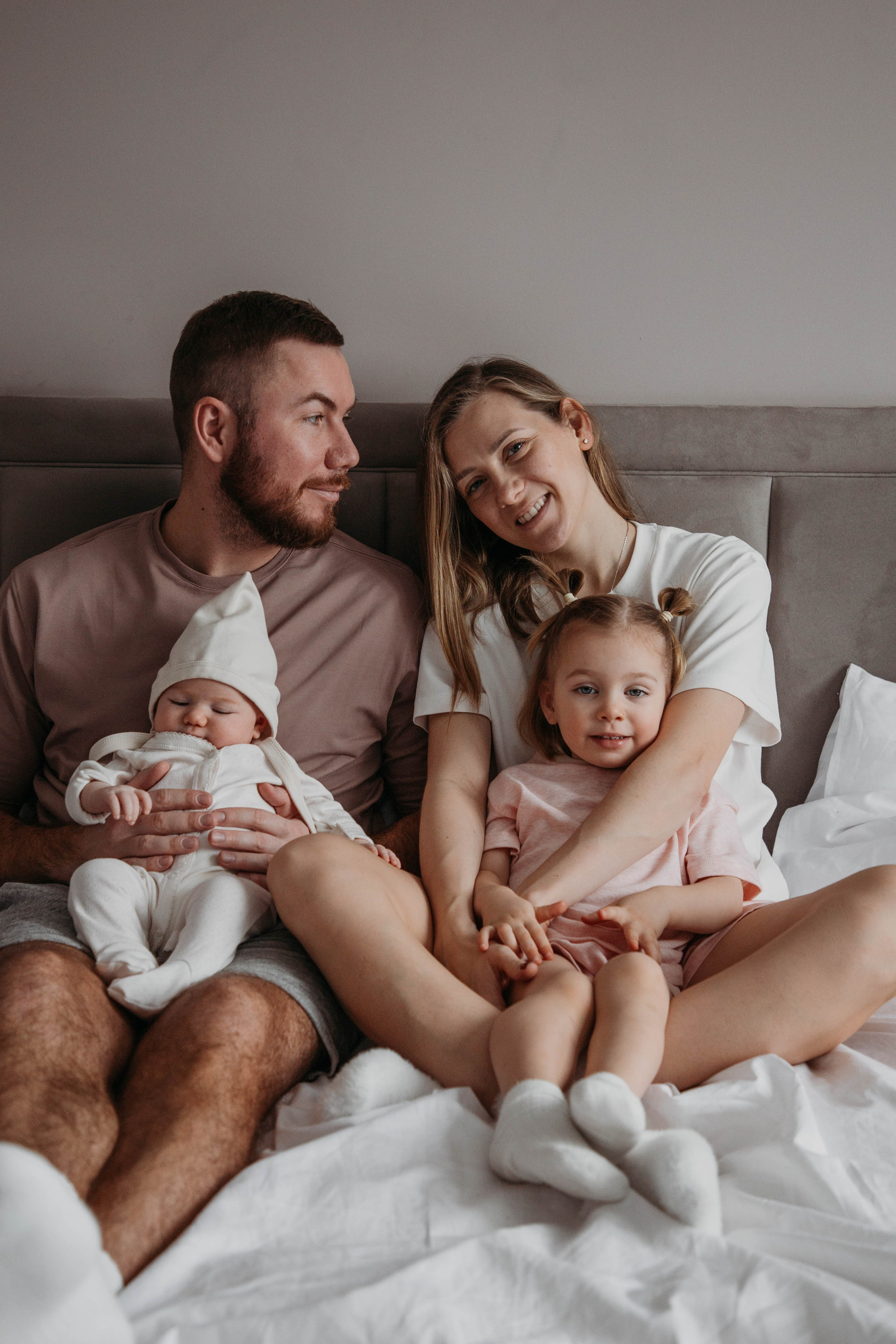 вся семья на кровати обнимается и радуется еще одному члену семьи