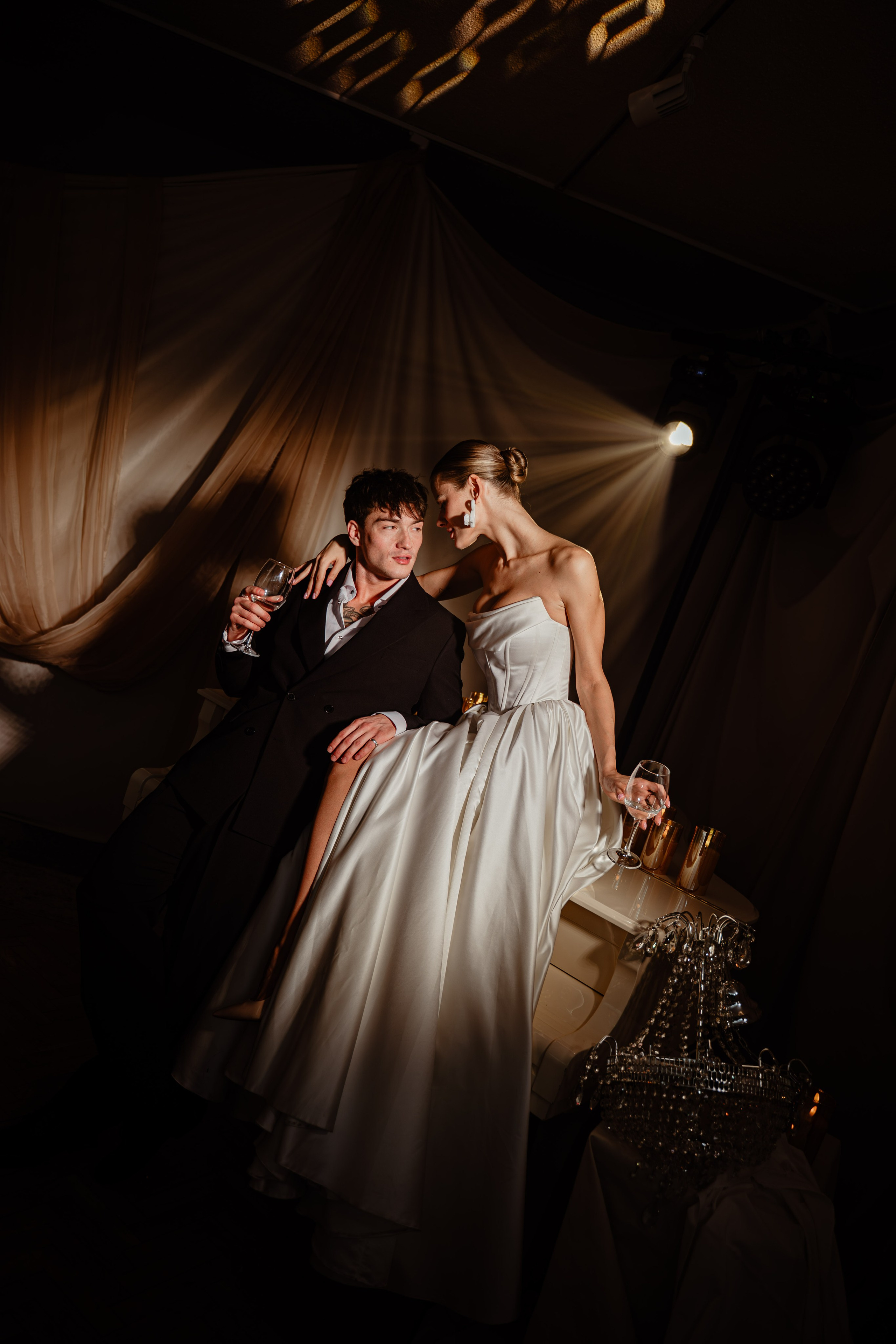 Жених и невеста улыбаются в полумраке банкетного зала — тёплая атмосфера