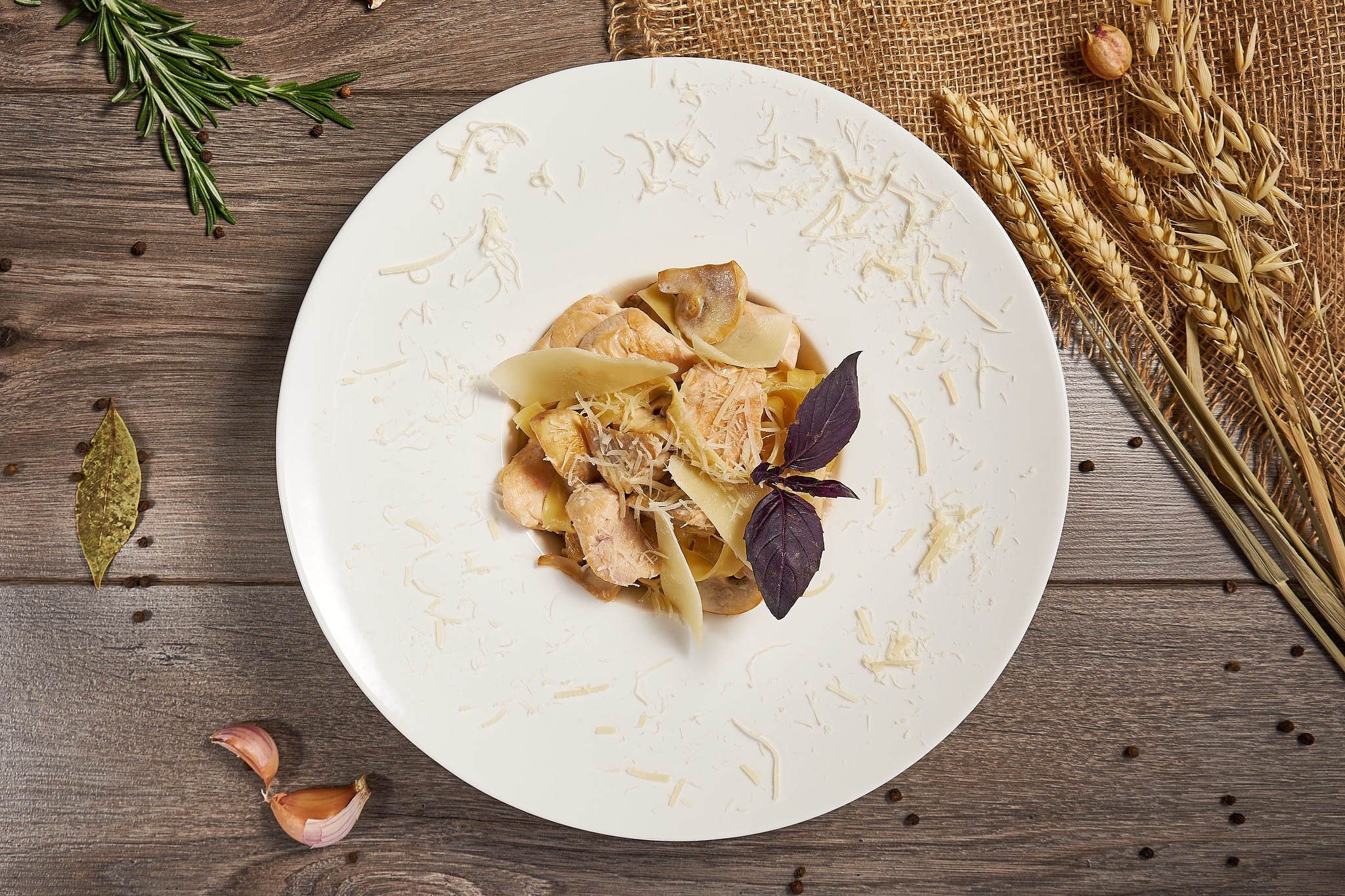 Паста с курицей, грибами и сыром пармезан на белой тарелке. Аутентичная подача с базиликом и натёртым сыром, съёмка на деревянном фоне