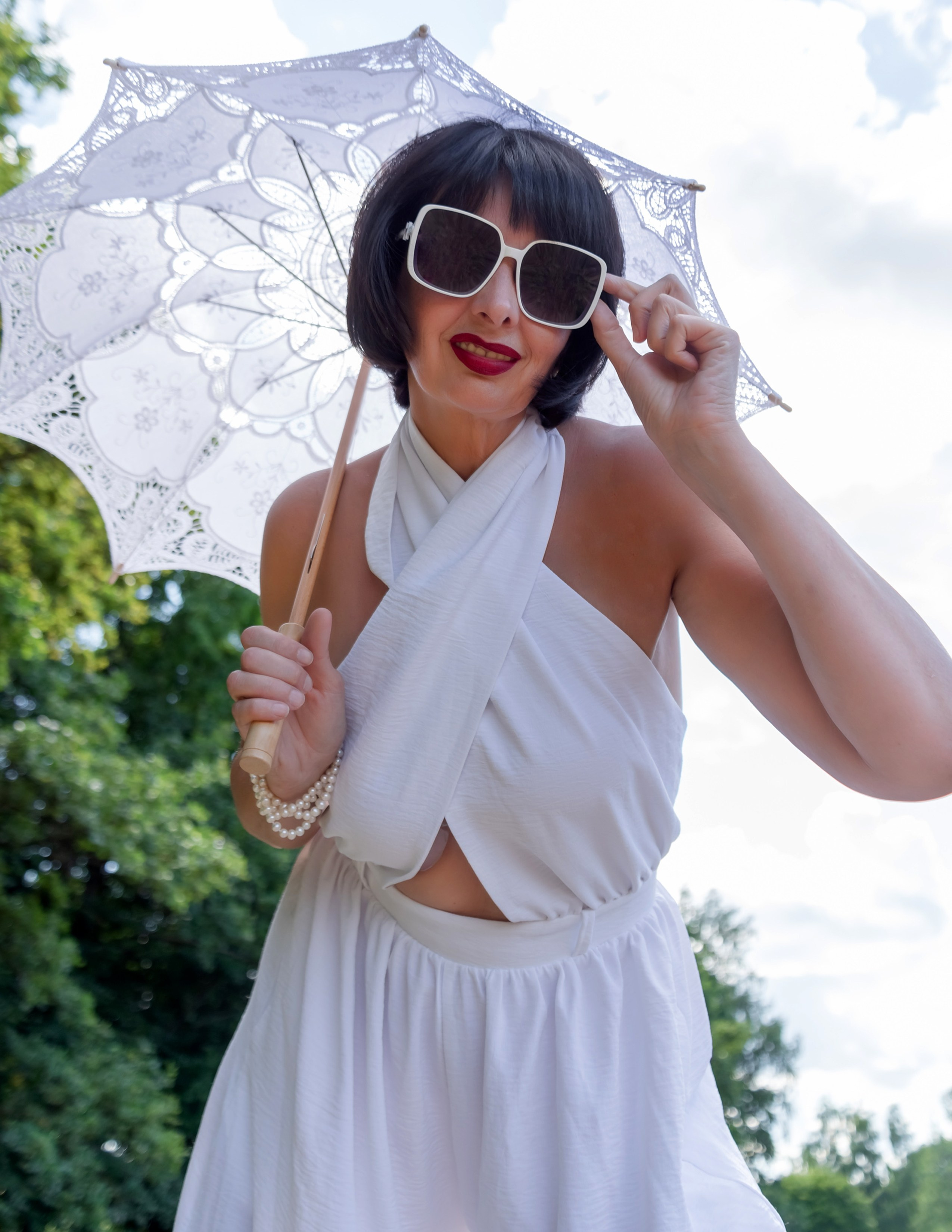 На фото девушка в поле с зонтом наклонилась вниз.