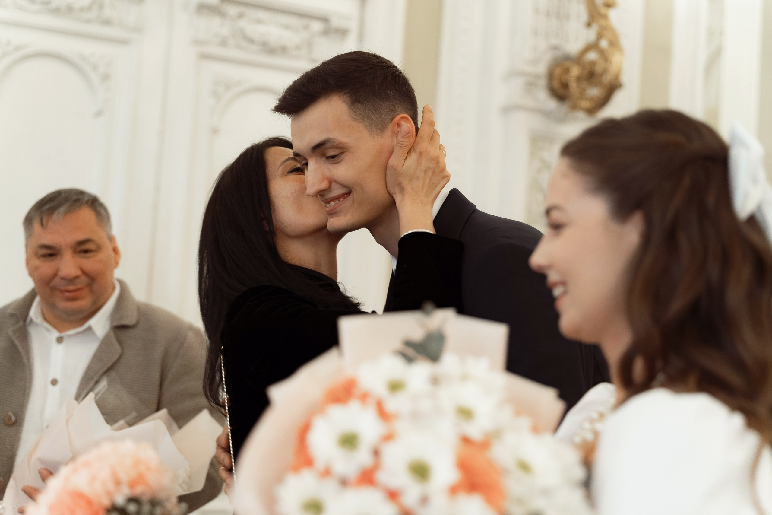 Гости и родственники поздравляют молодожёнов в зале дворца бракосочетания
