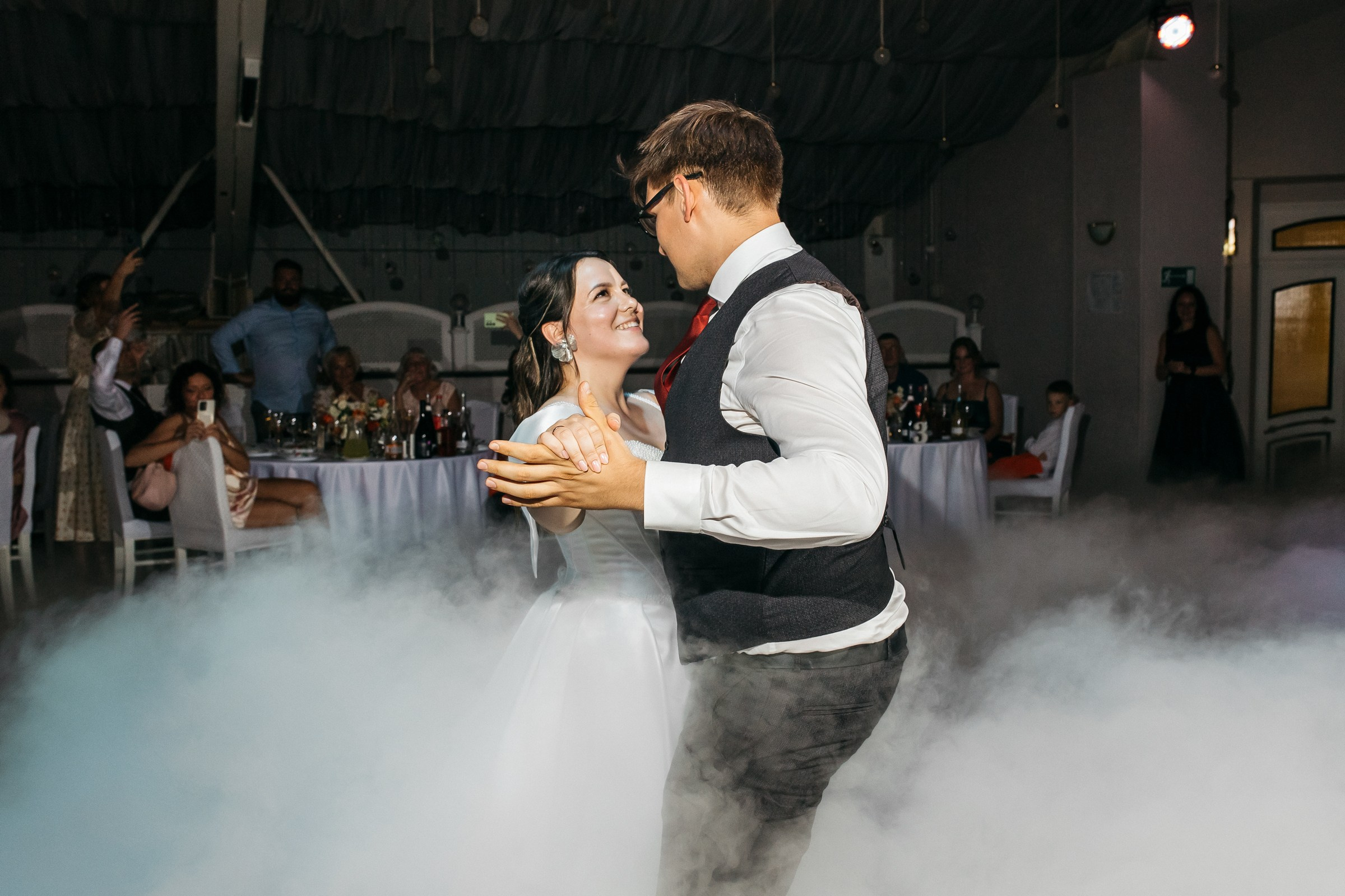 Красивый танец жениха и невесты на их свадебном банкете в облаках дыма.
