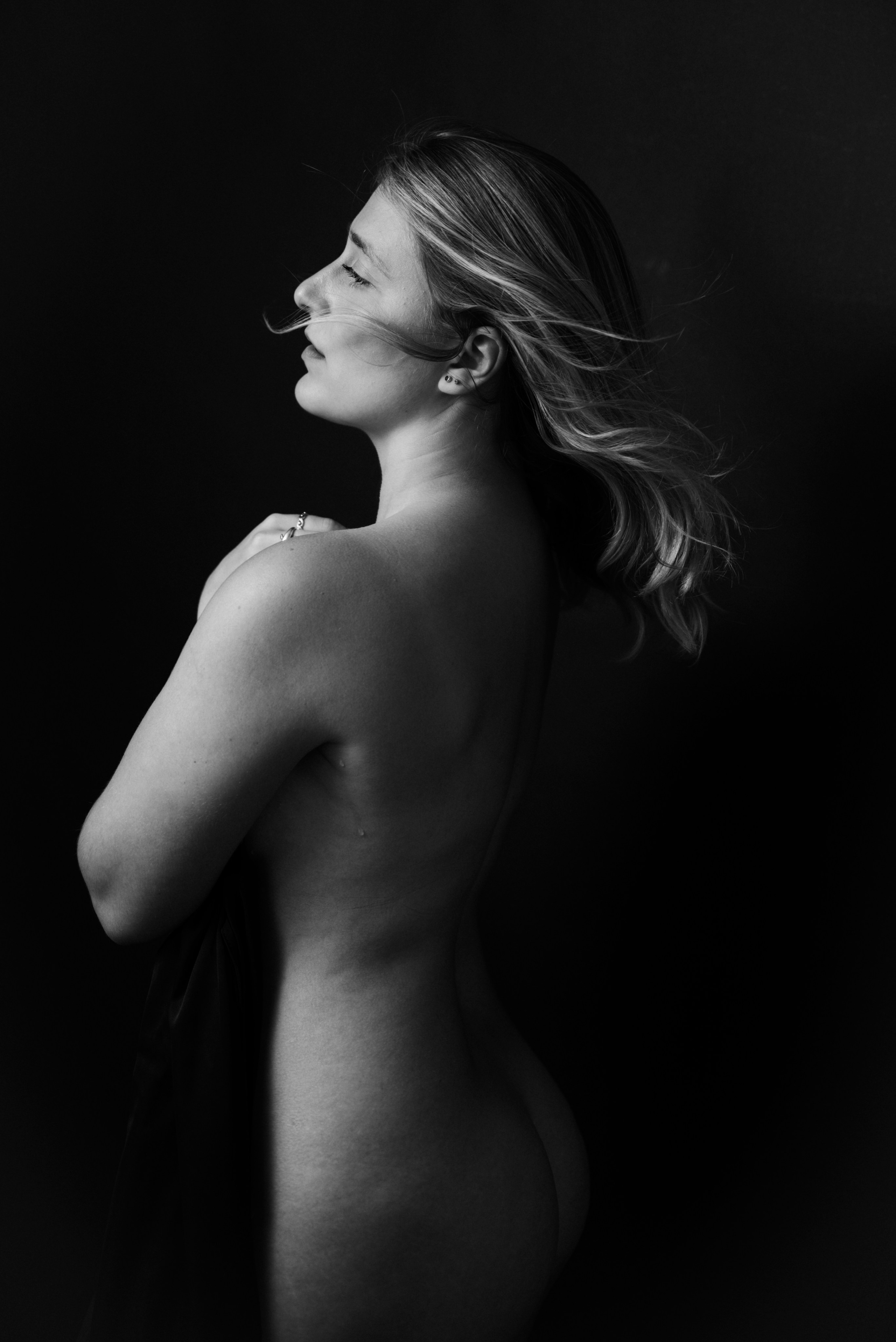 Artistic boudoir photography London — sensual side profile with flowing hair, soft natural expression