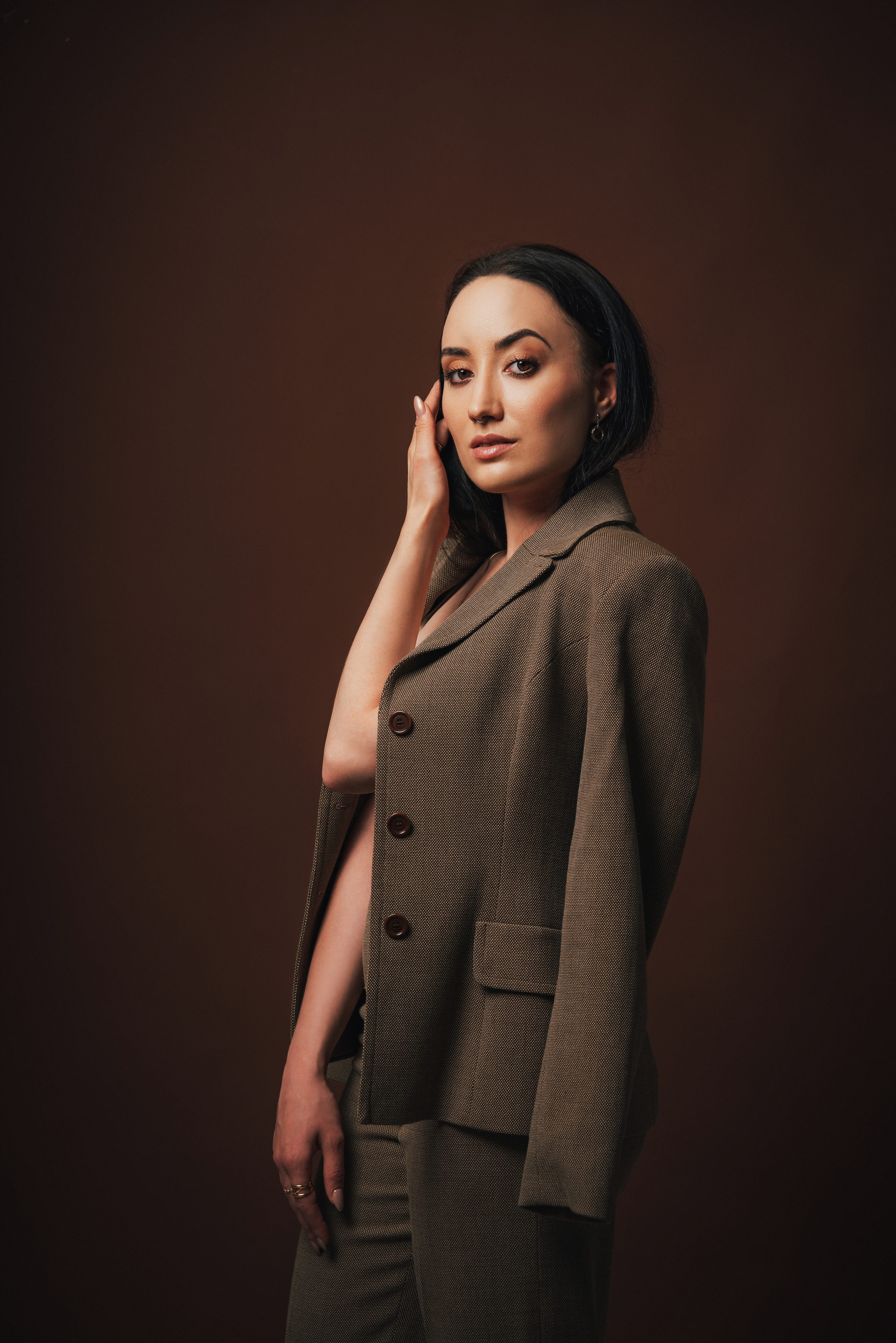 Фотоссесия в спб. Портрет красивой девушки в костюме на коричневом фоне. Позы для фотоссесии.