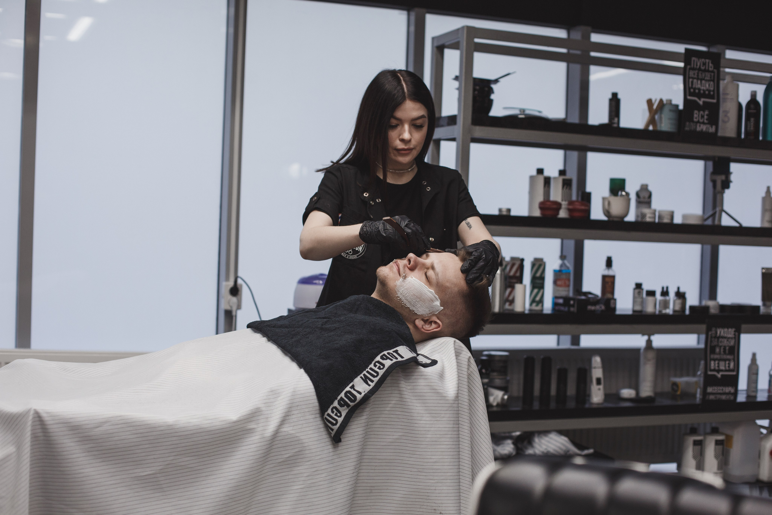 Бритье бороды бритвой в барбершопе.