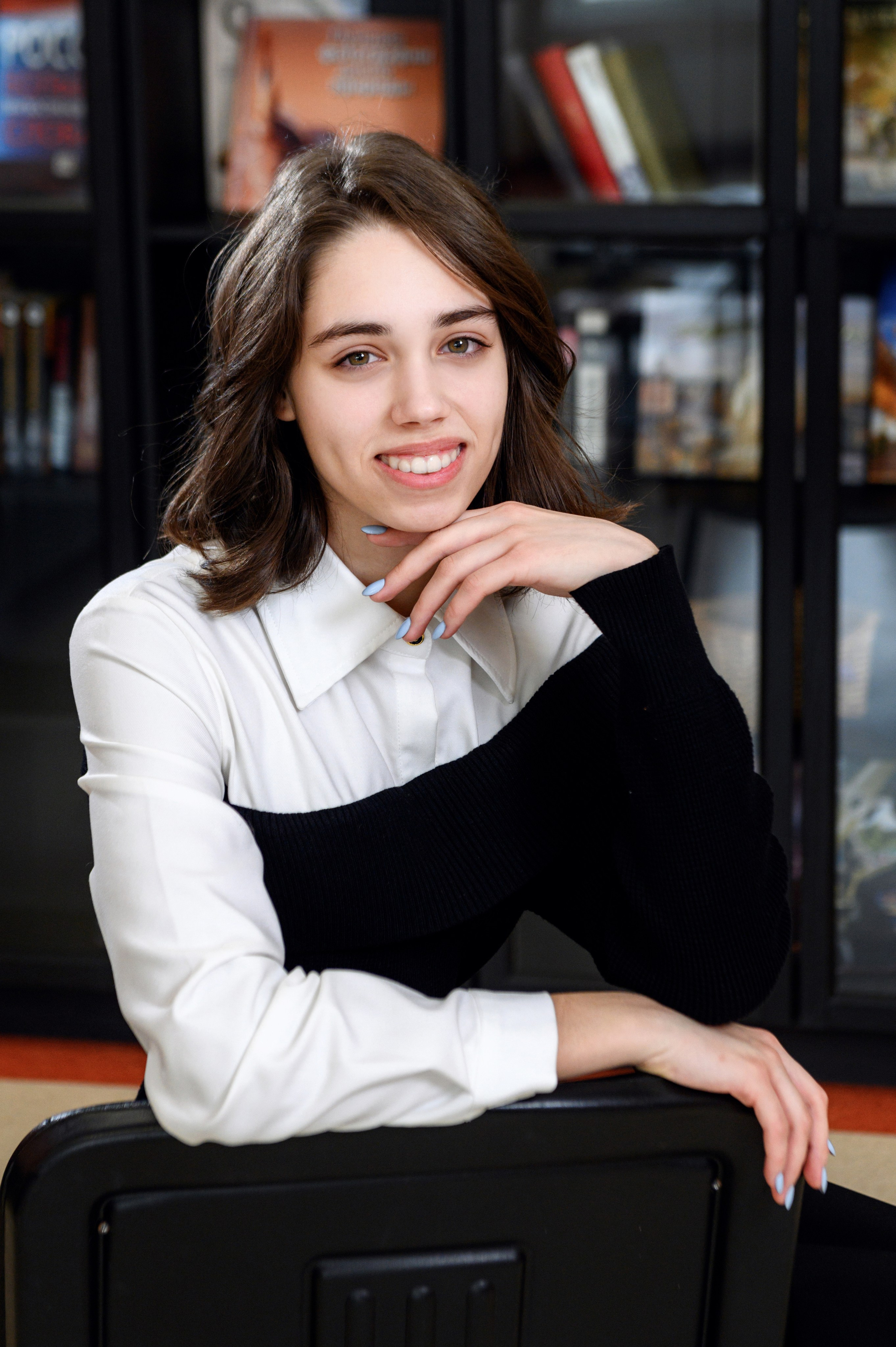 Портрет старшеклассницы у книжных полок.