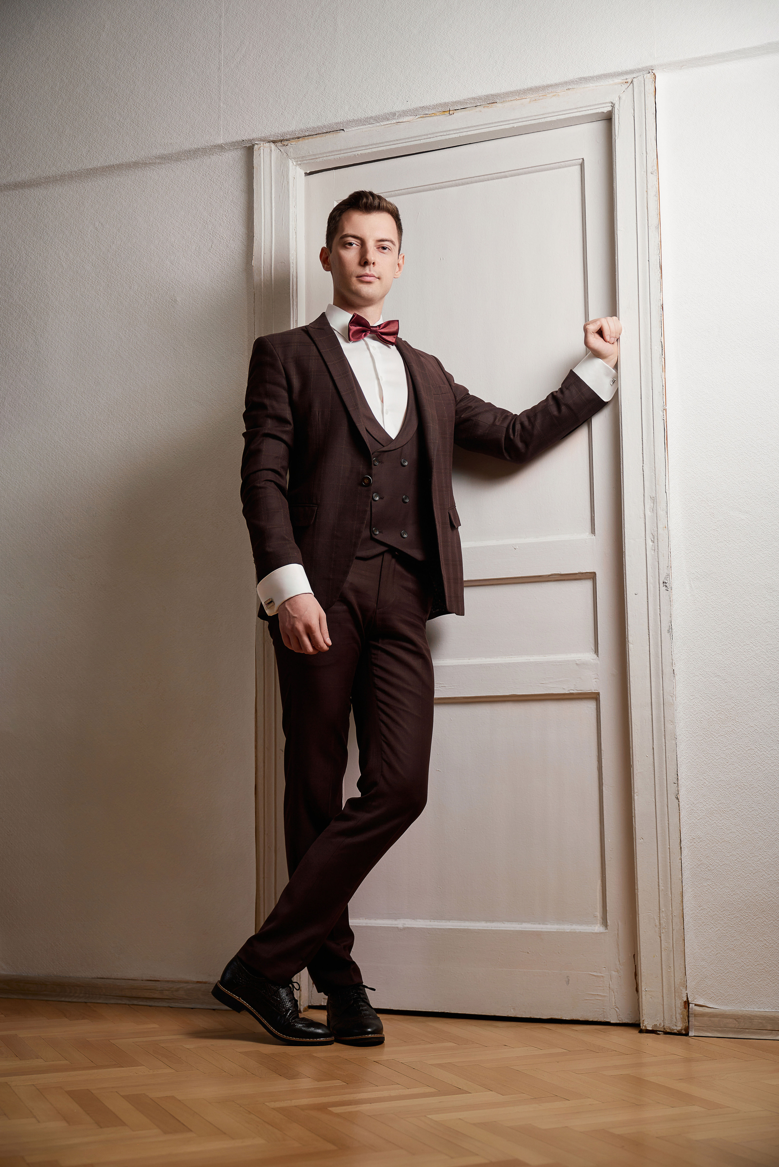 Жених в свадебном костюме стоит у двери