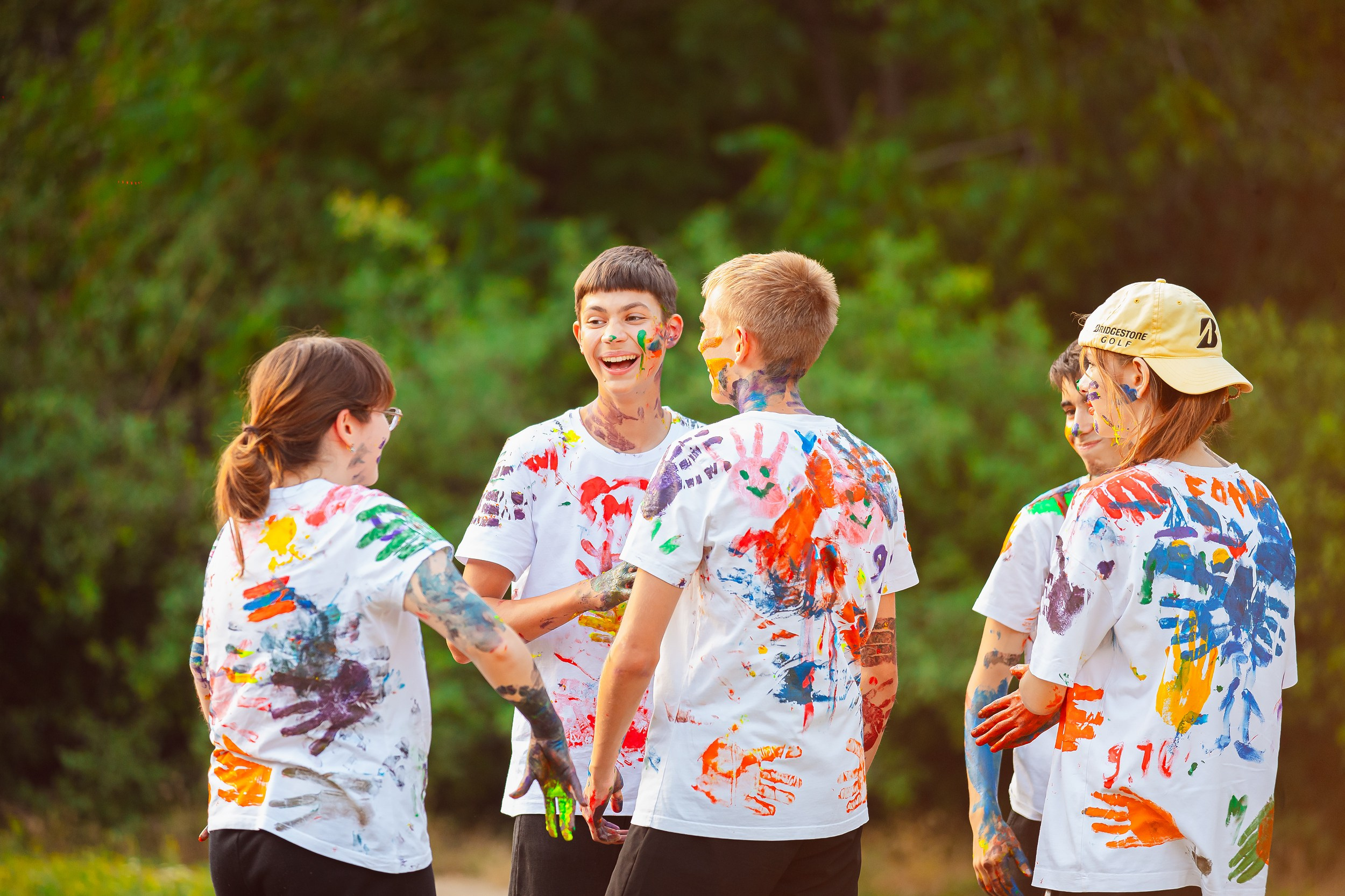 Школьники в белых футболках разукрашивают друг друга пальчиковыми красками