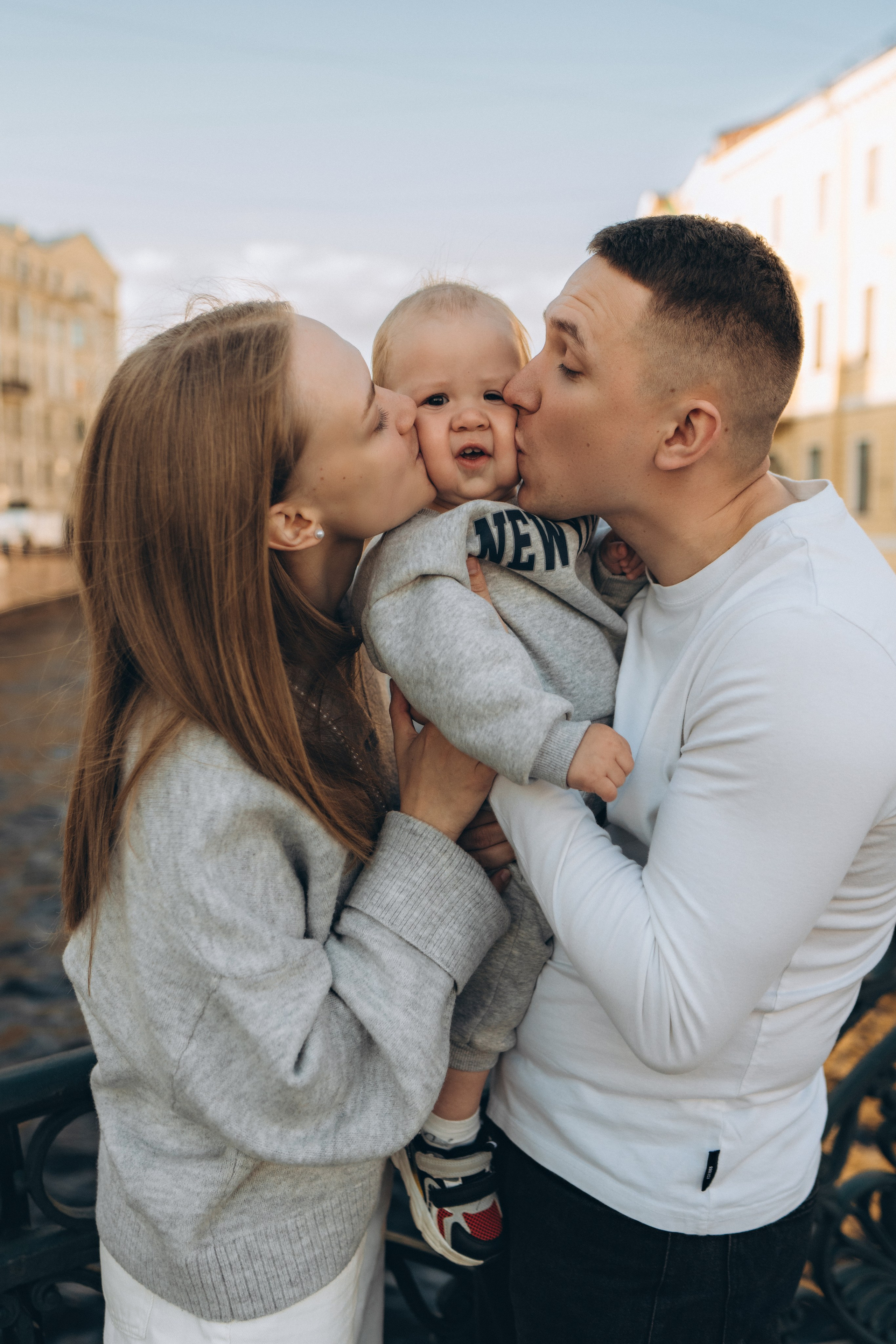 Родители обнимают ребёнка во время семейной фотосессии в центре Санкт-Петербурга