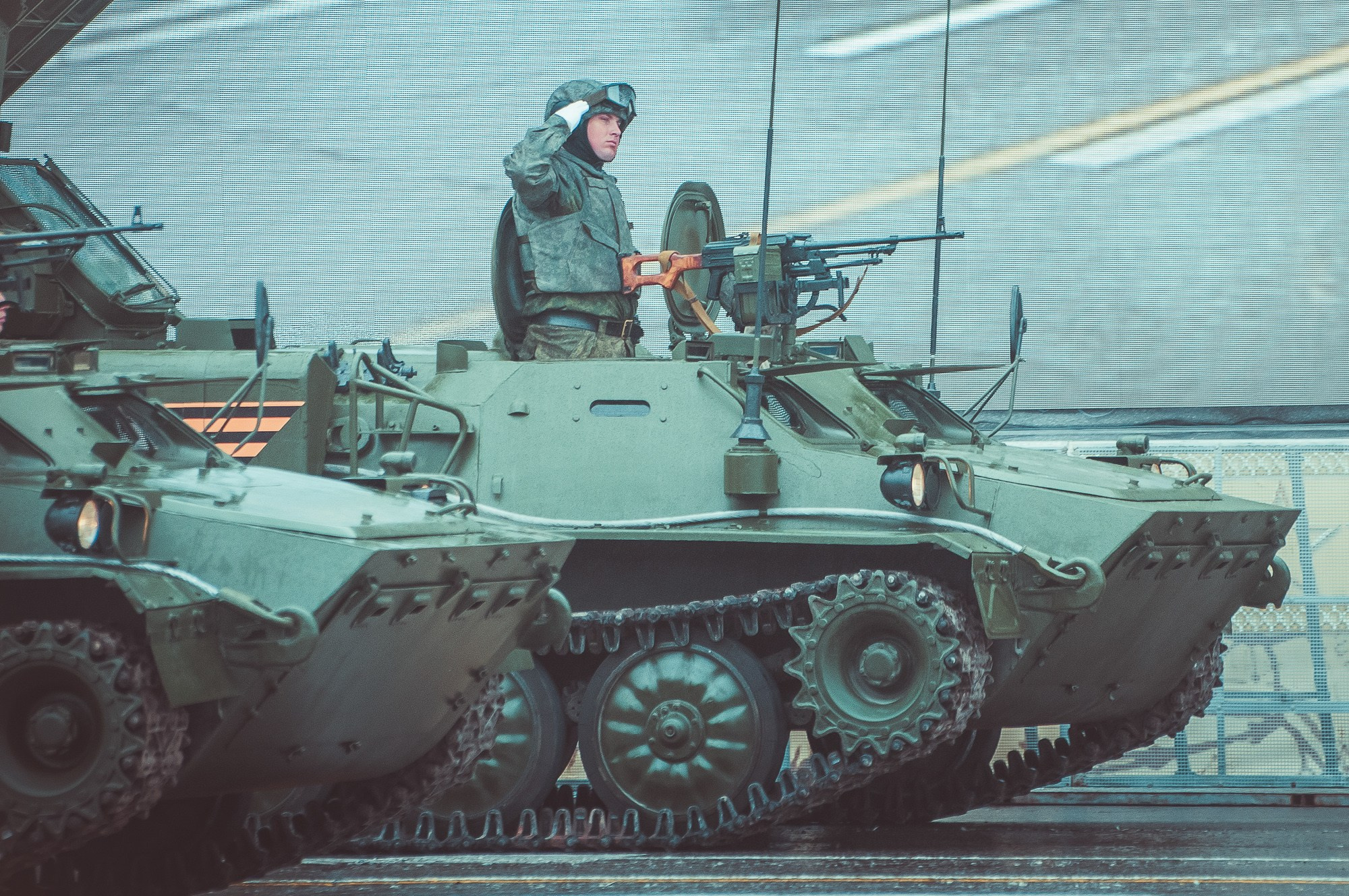 Военнослужащий отдаёт честь, стоя в кабине военной техники