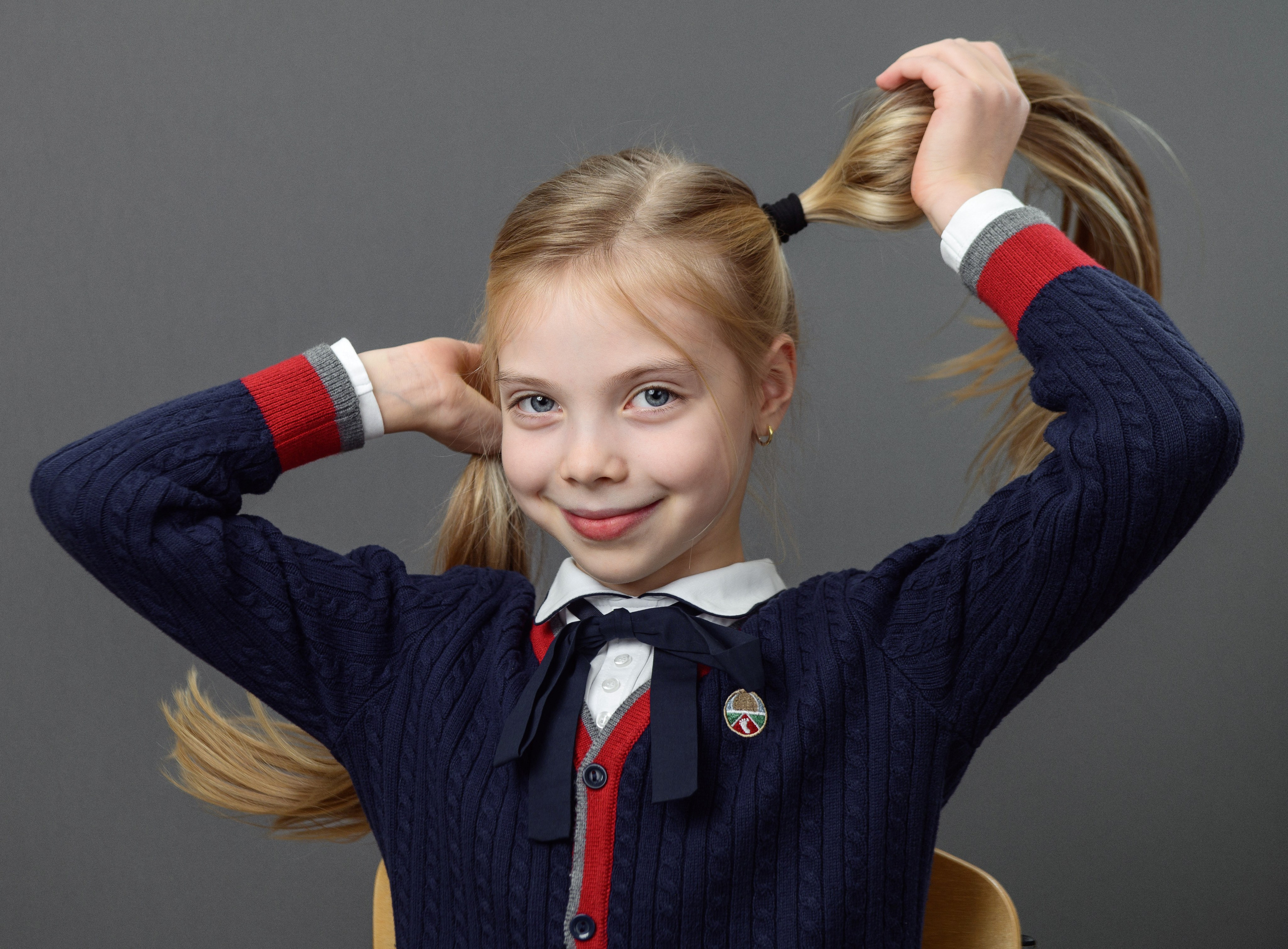 Школьница в синей форме с двумя хвостиками и поднятыми руками