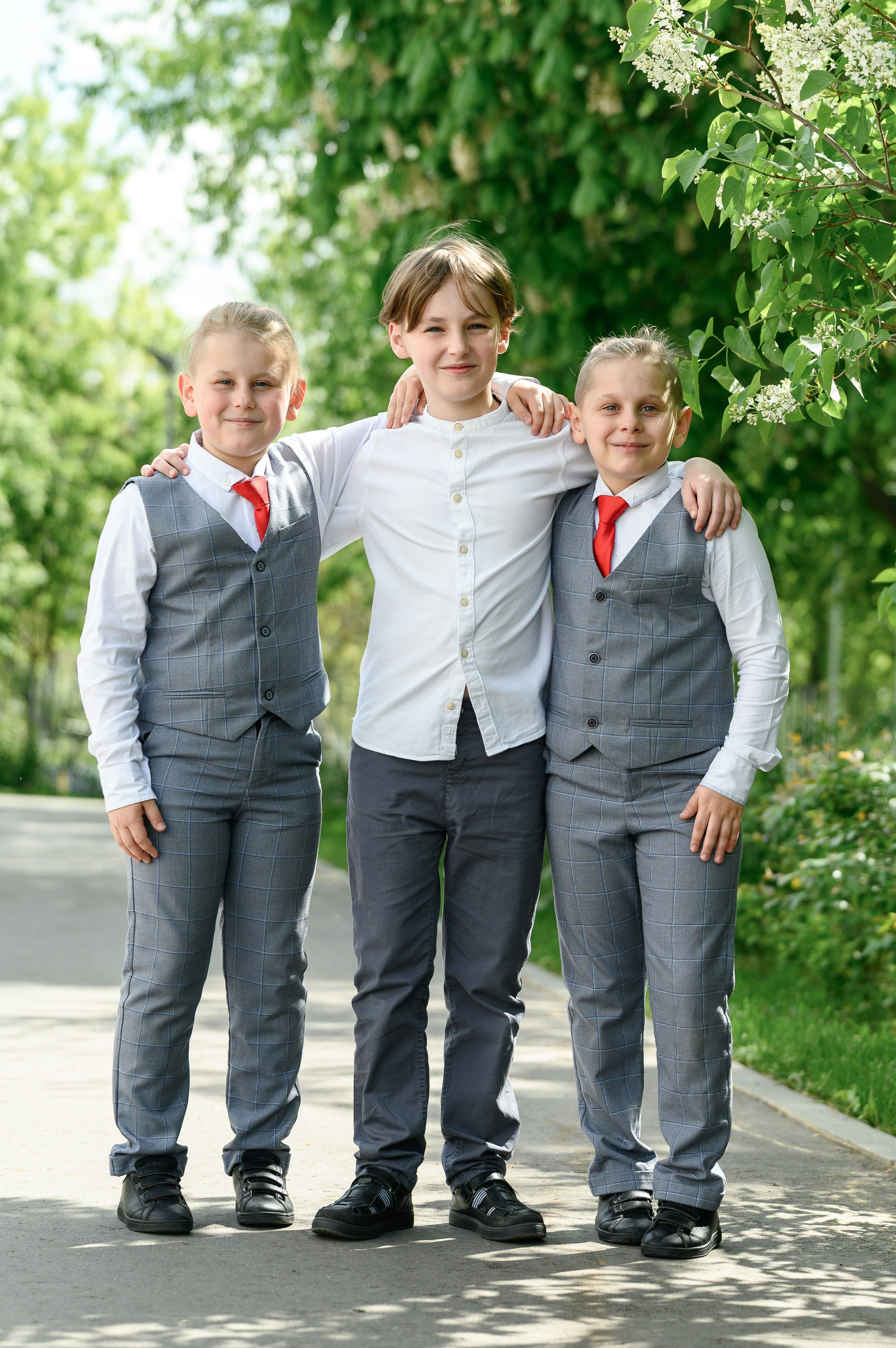 Трое школьников начальных классов на прогулке у деревьев