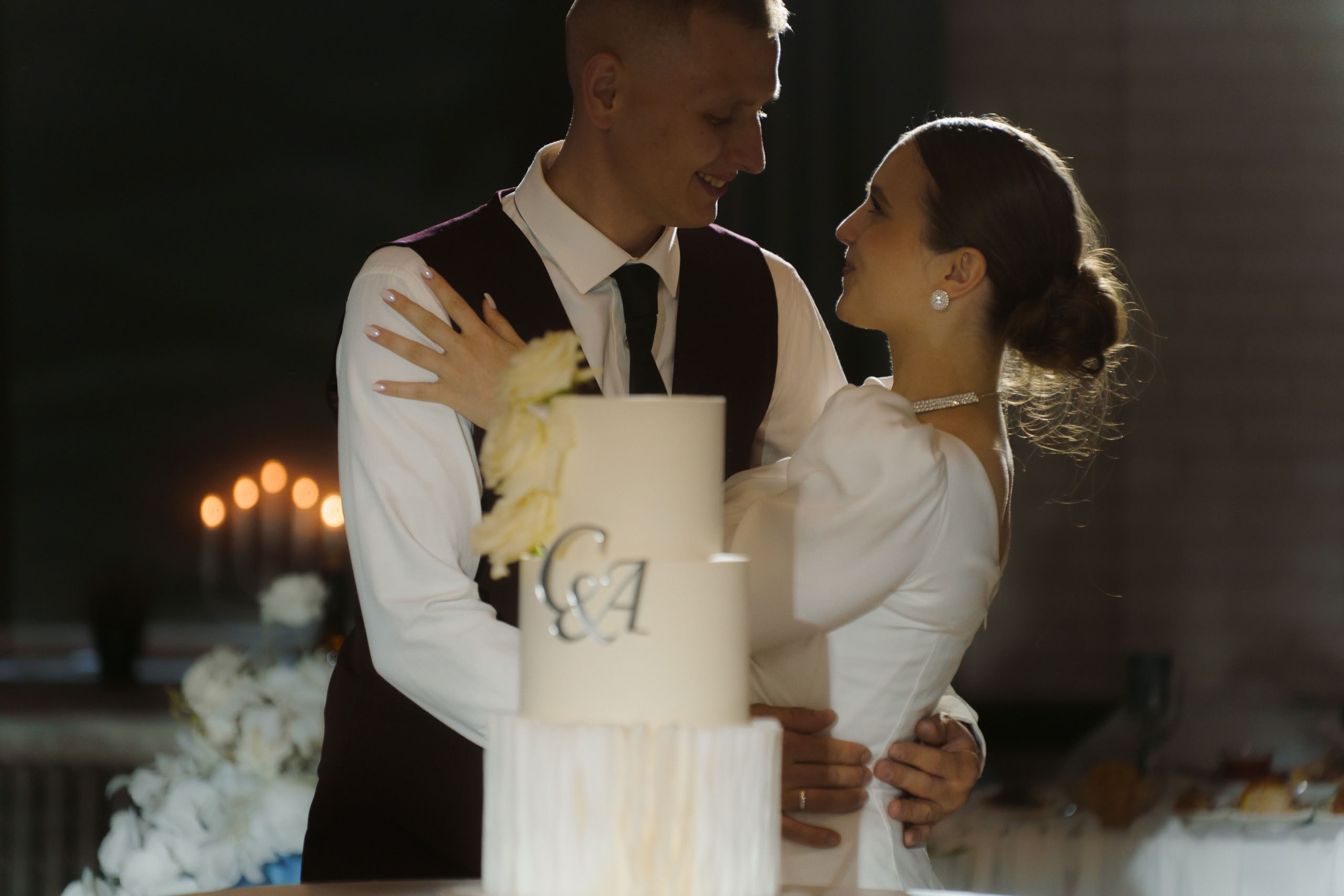 Пара обнимается перед разрезанием свадебного торта