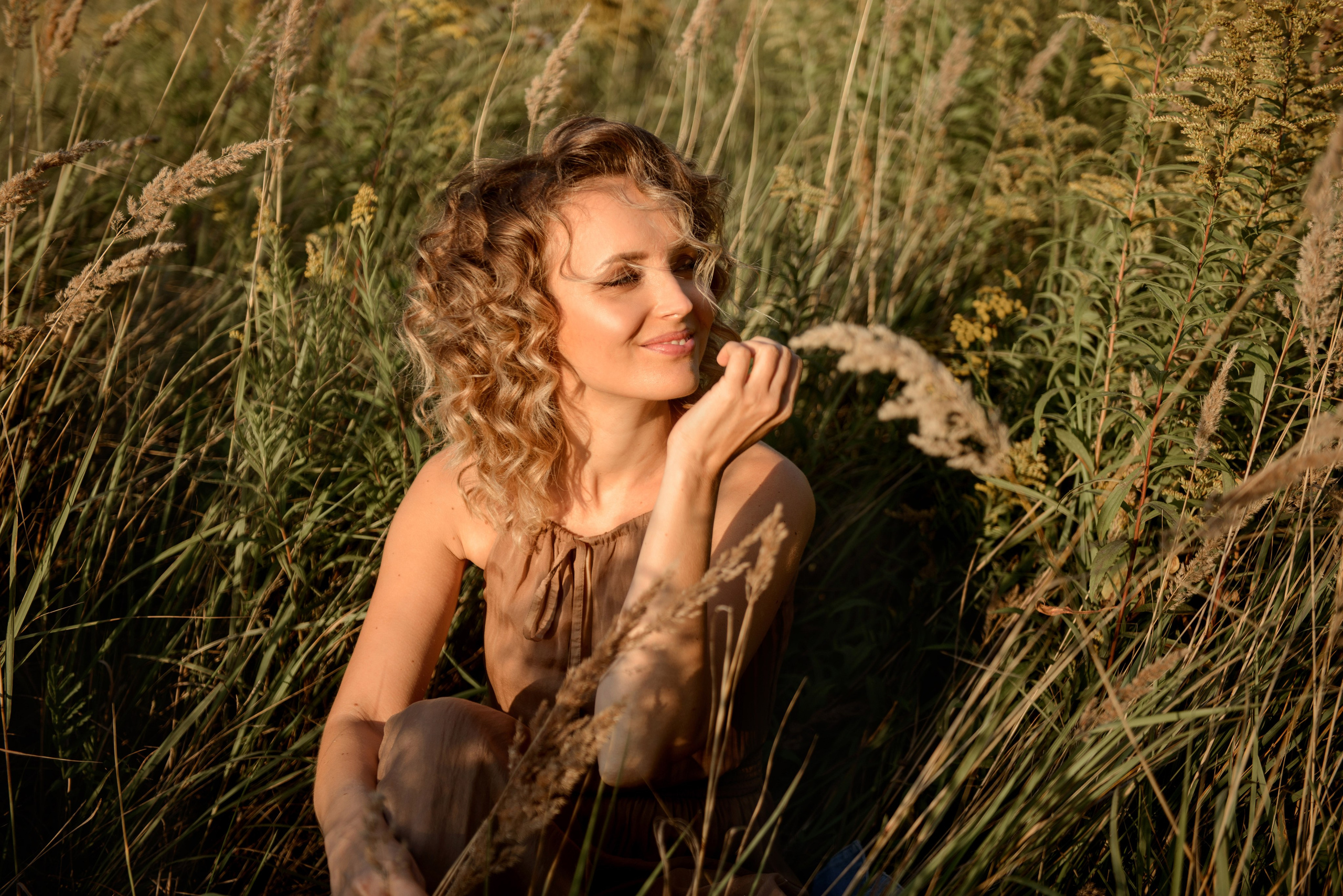 A photo shoot for a woman l in the field. Sunset photo shoot for a girl Curly hair style. (photographer in Edinburgh Elena)