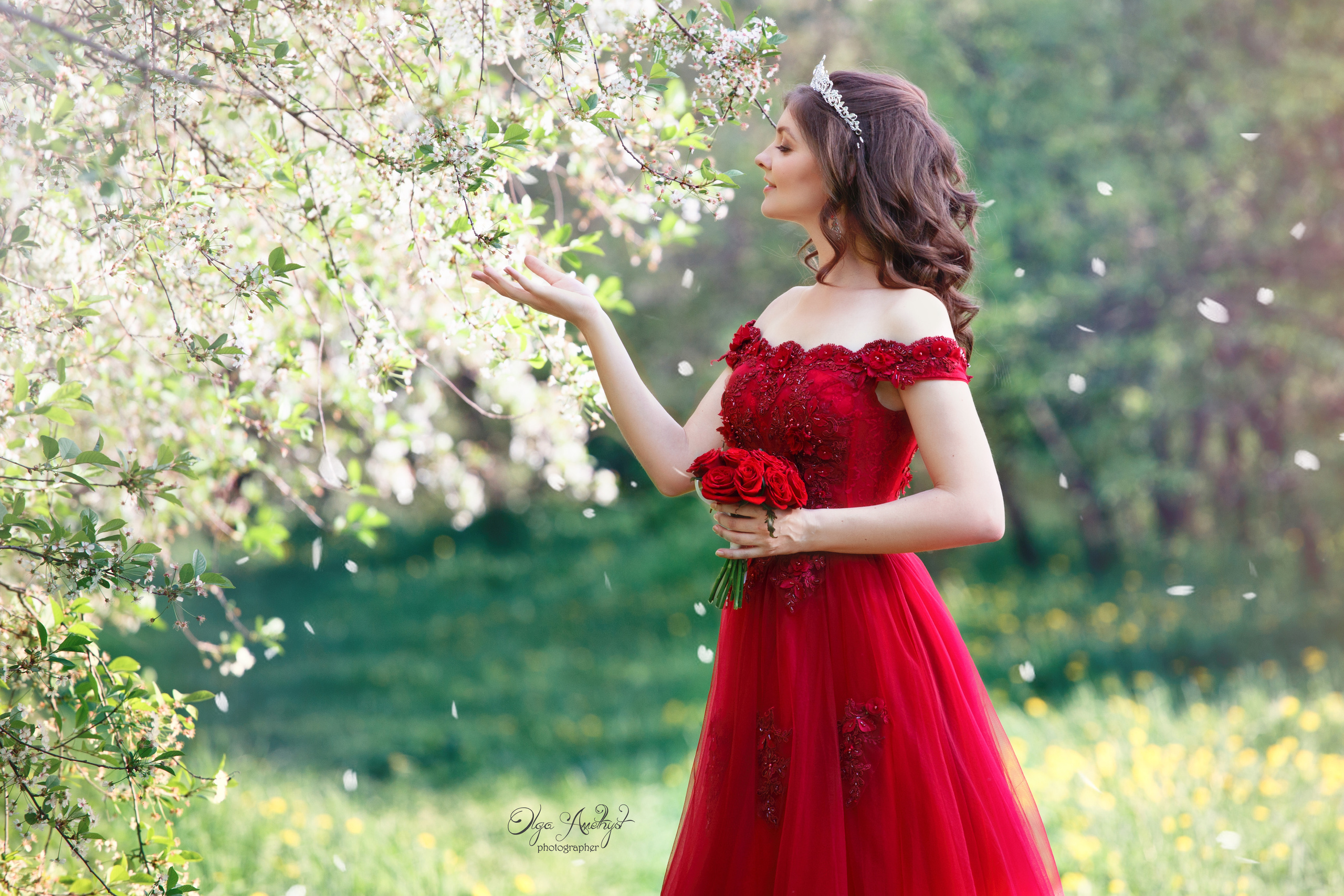 Девушка фотографируется на фоне цветущих деревьев парке