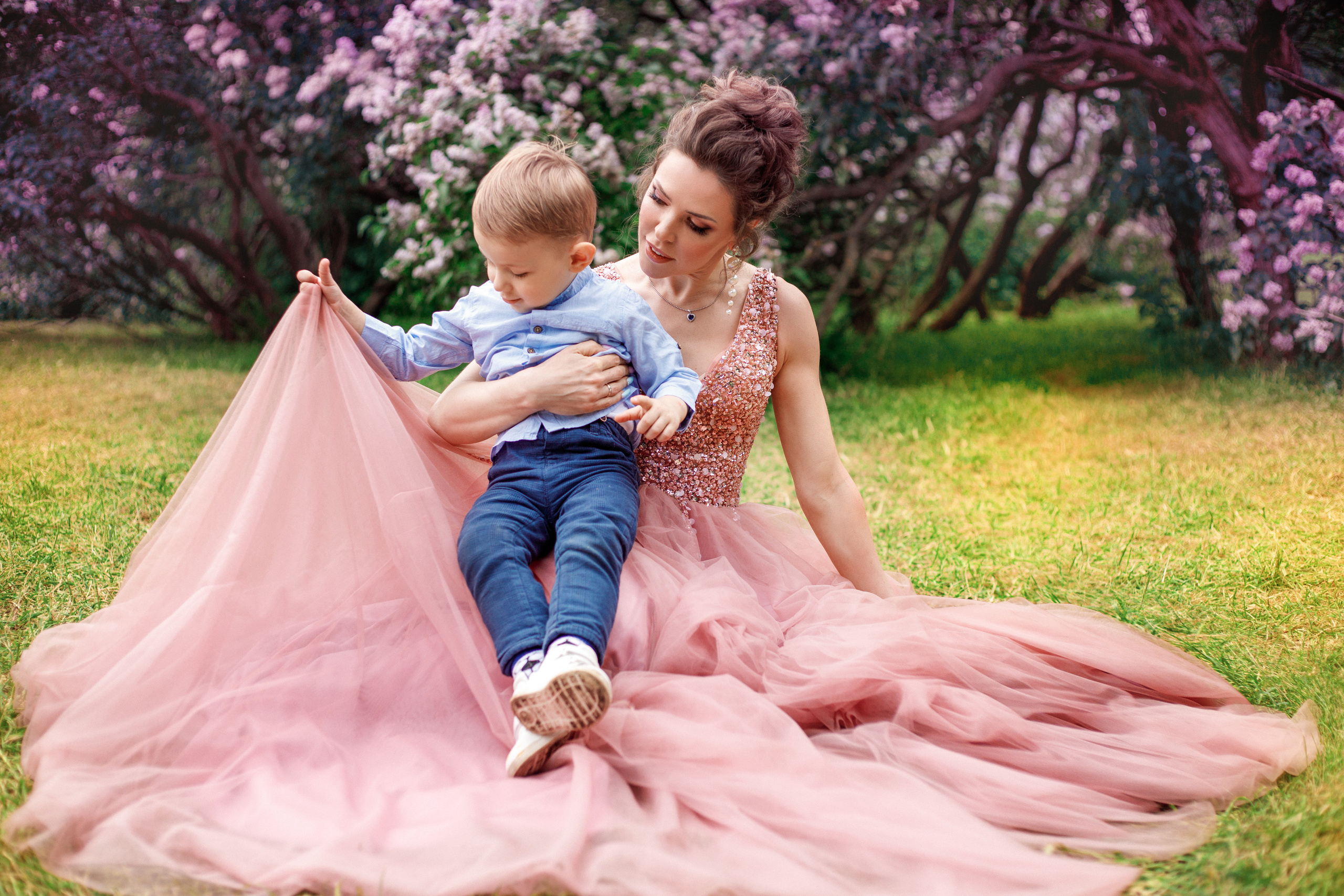 Мама и сын фотографируются на фоне сиреневых деревьев