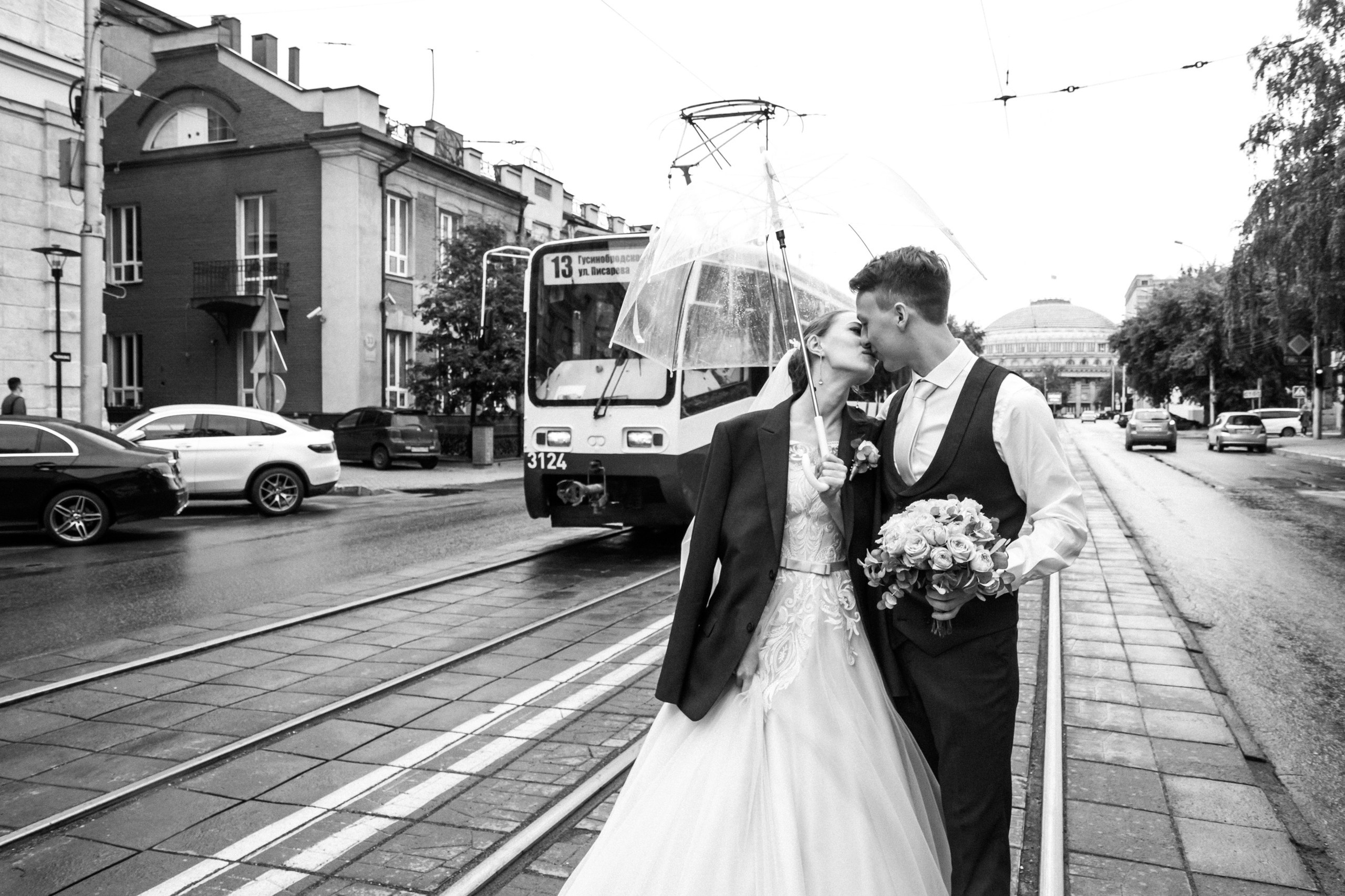 Свадебная фотосесия в Новосибирске: жених и невеста целуются на фоне 13-го трамвая