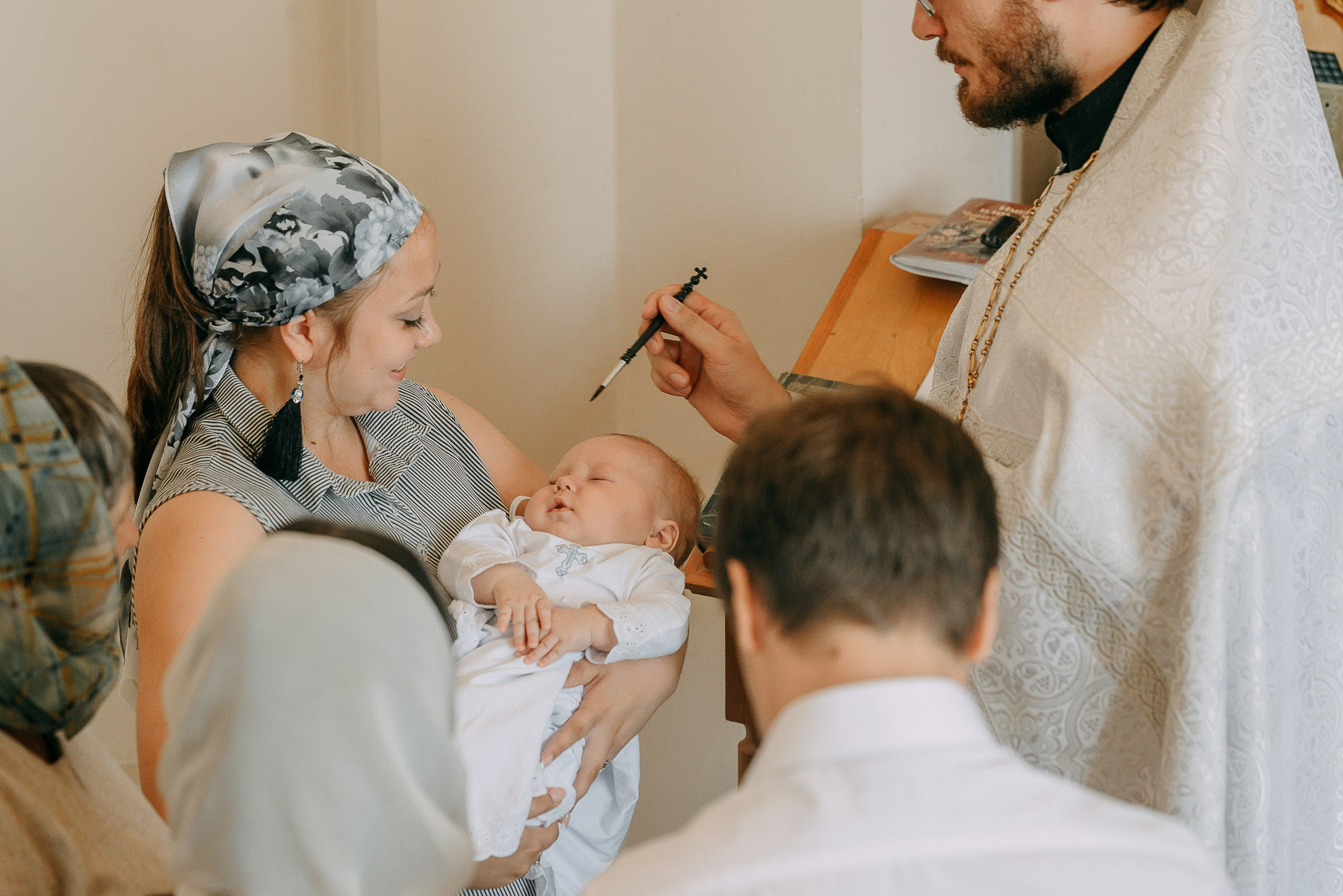 Фотограф на крещение, съемка таинства миропомазания младенца в храме.