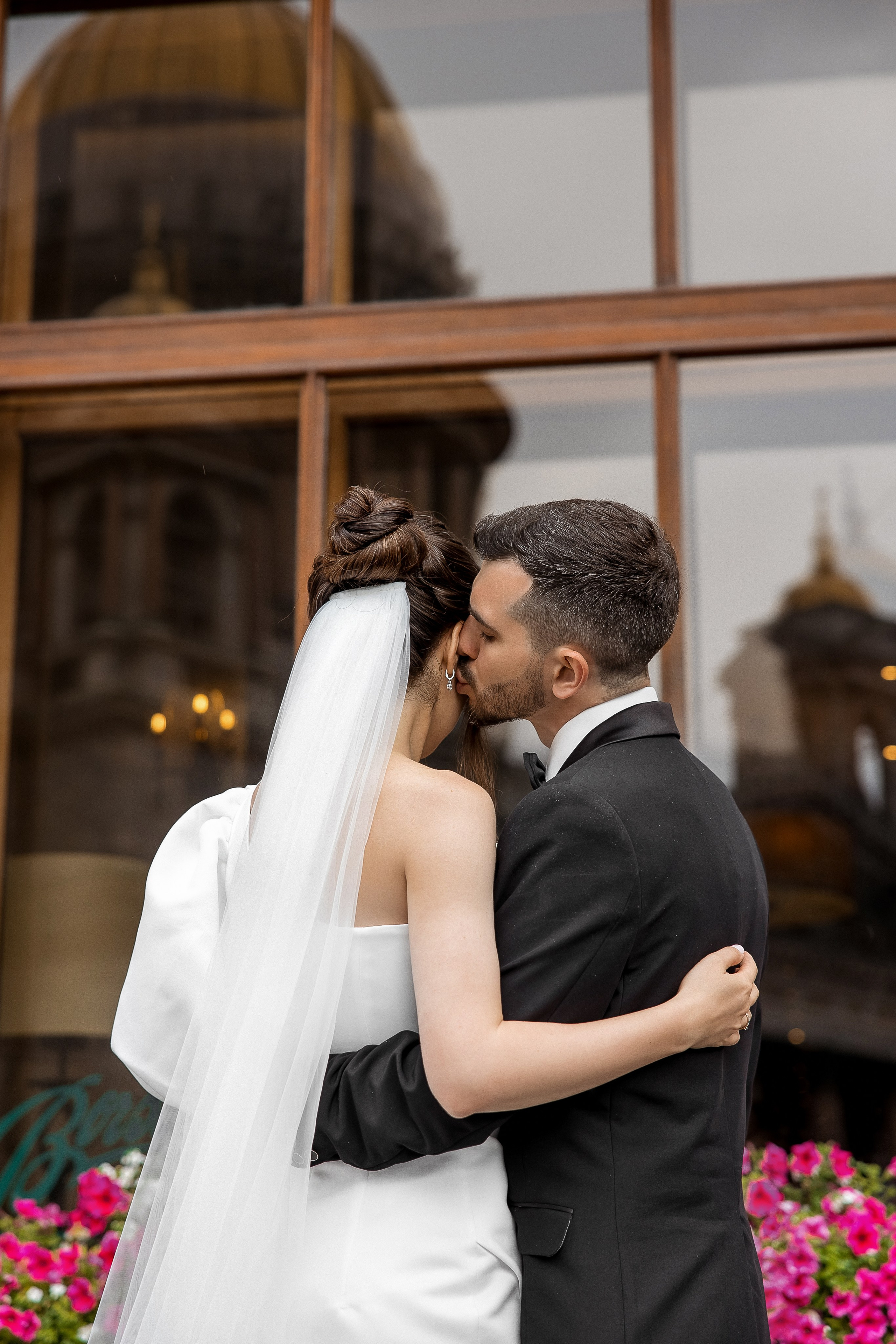 Портрет жениха и невесты на фоне окна в котором отражается купол Исаакиевского собора