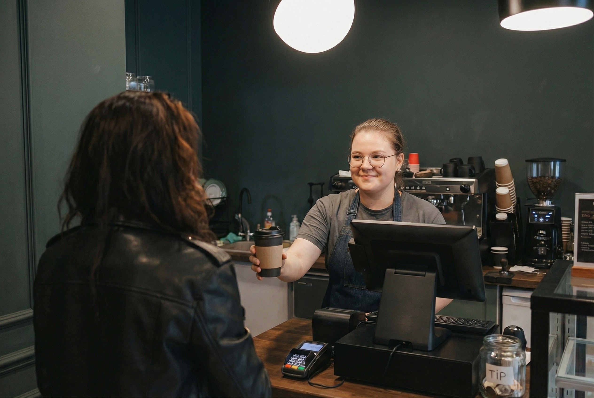 Процесс передачи заказа: бариста отдает кофе клиенту.