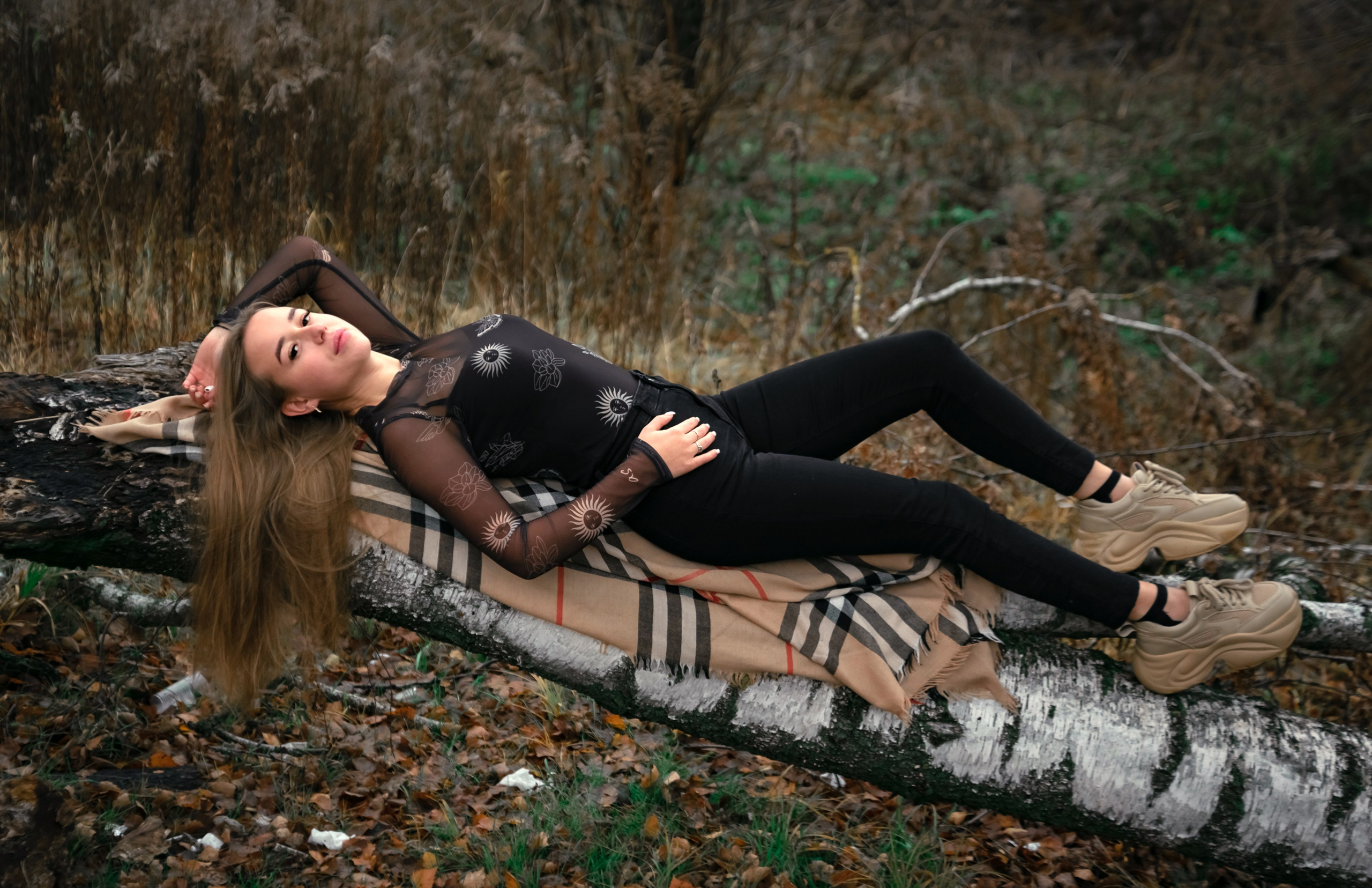 На фото девушка лежит на дереве осенью.