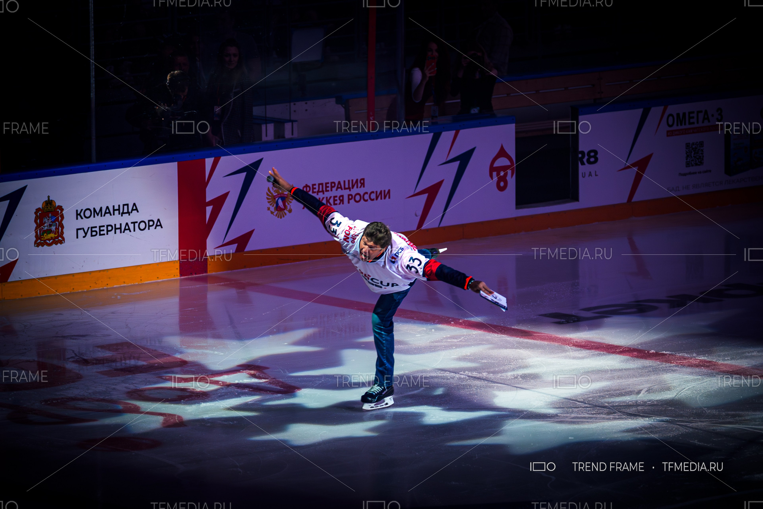 Финал Кубка Овечкина 2025 по хоккею — Дмитрий Губерниев выполняет ласточку на льду с микрофоном. Премиальные спортивные фото TrendFrame.