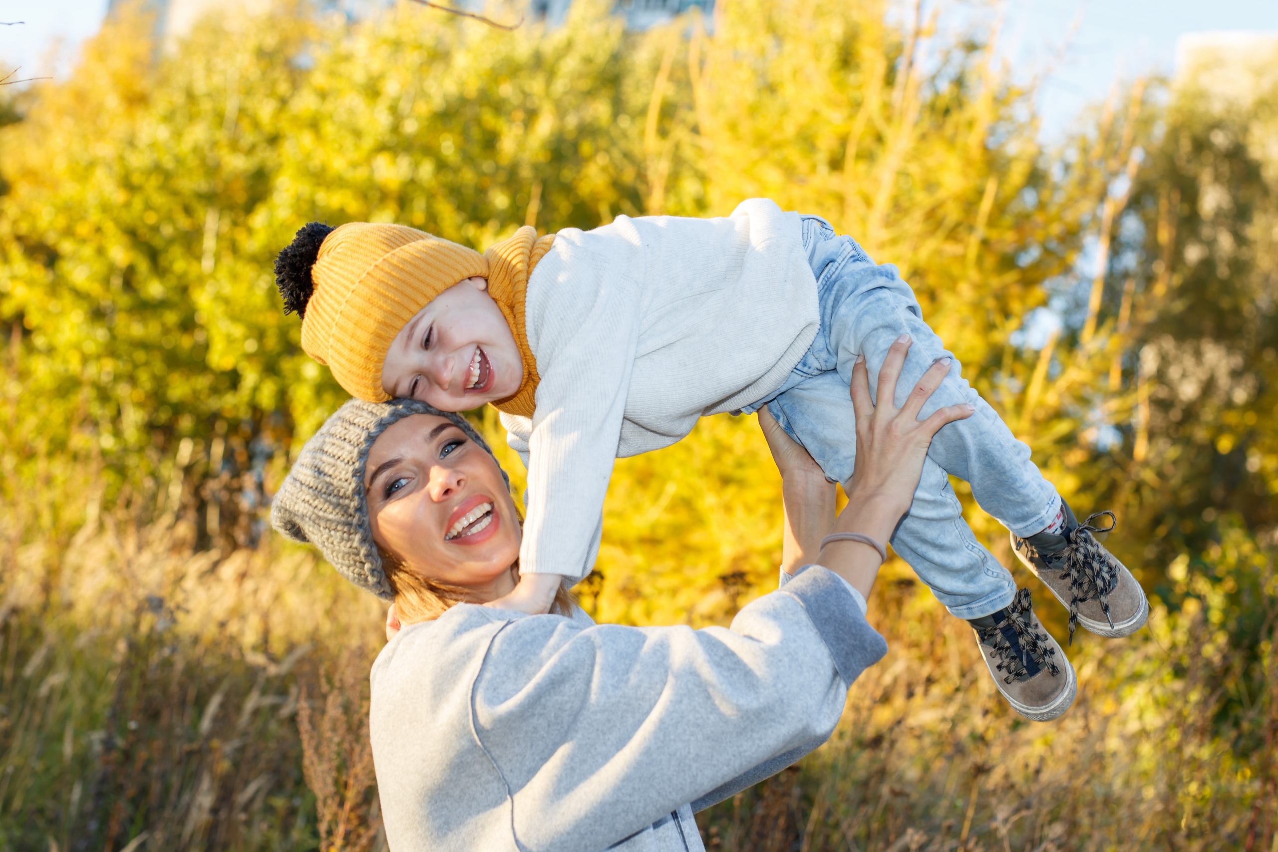 Мама и сын в ярких шапках радуются на осенних фотографиях