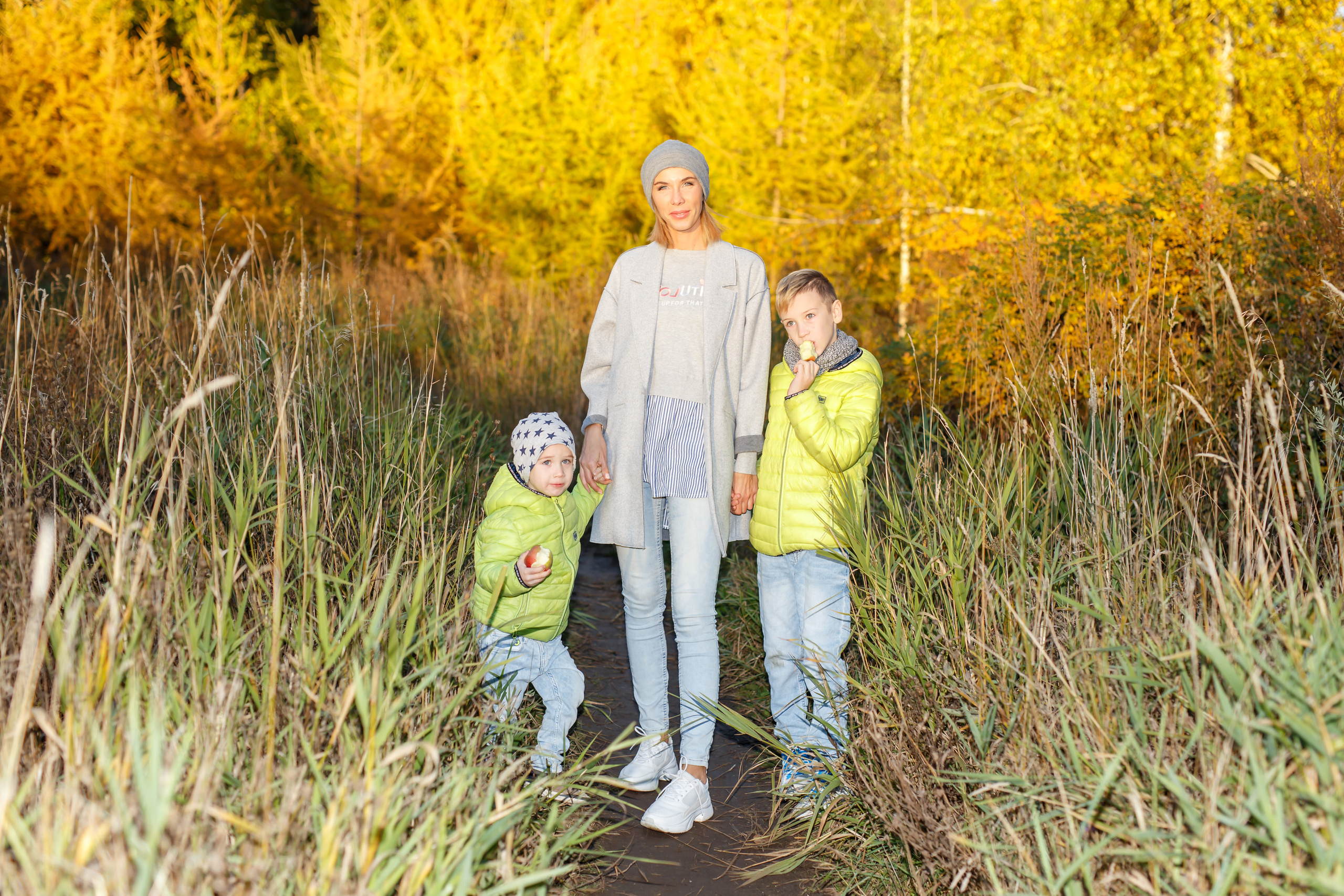 Мама с детьми позирует на фоне осеннего желтого леса