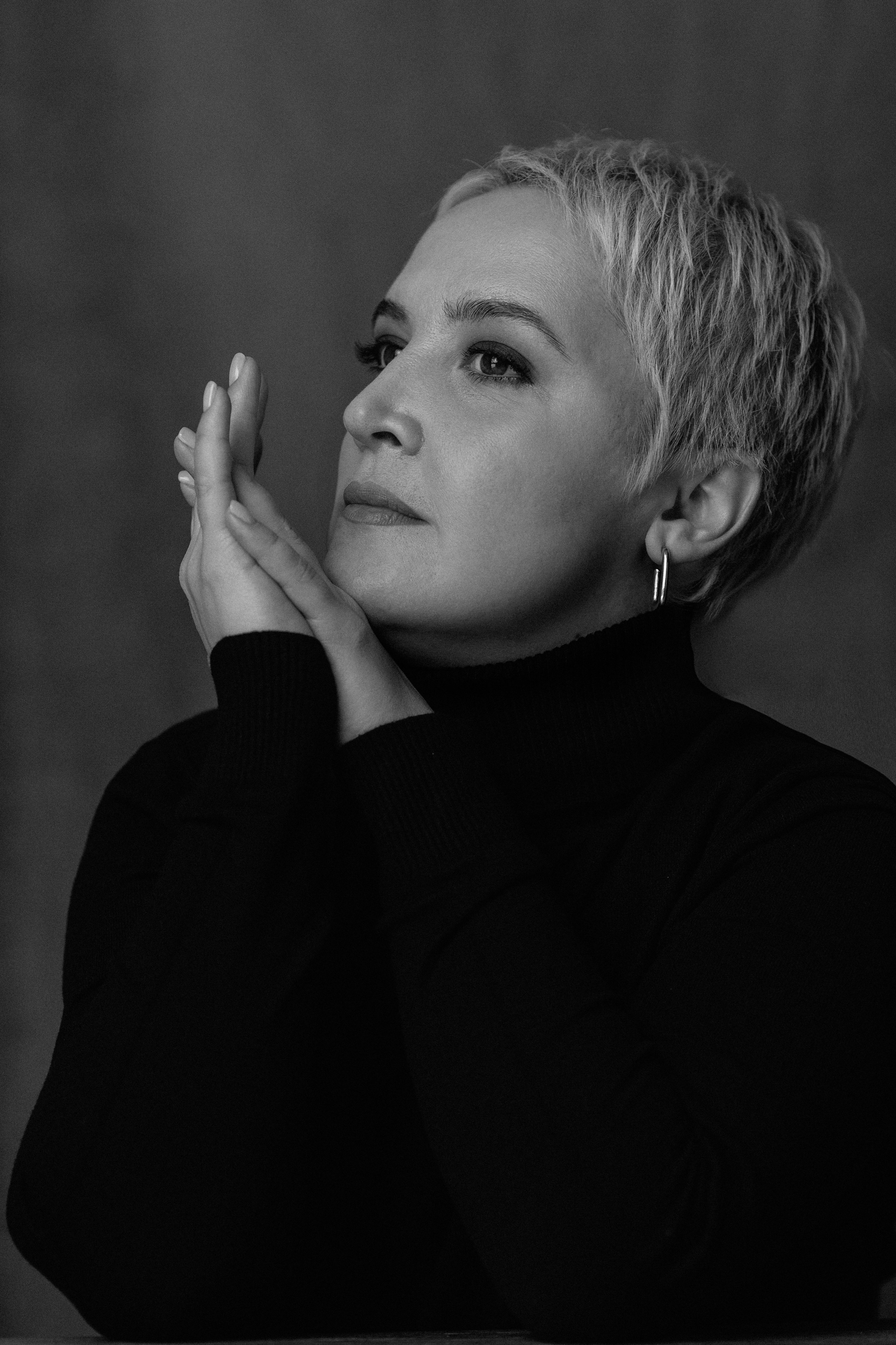 Чёрно-белый портрет женщины в студии, естественная поза, мягкий свет, минималистичный фон