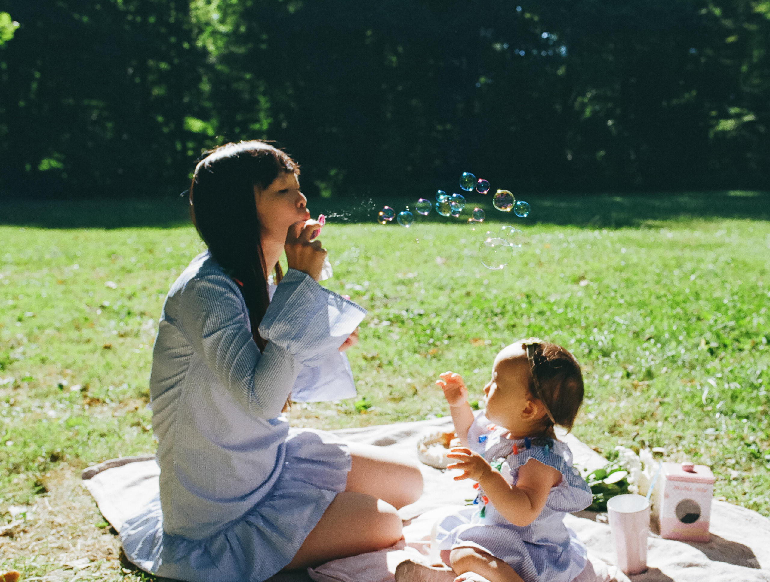 a mother blowing bubbles with her daughter