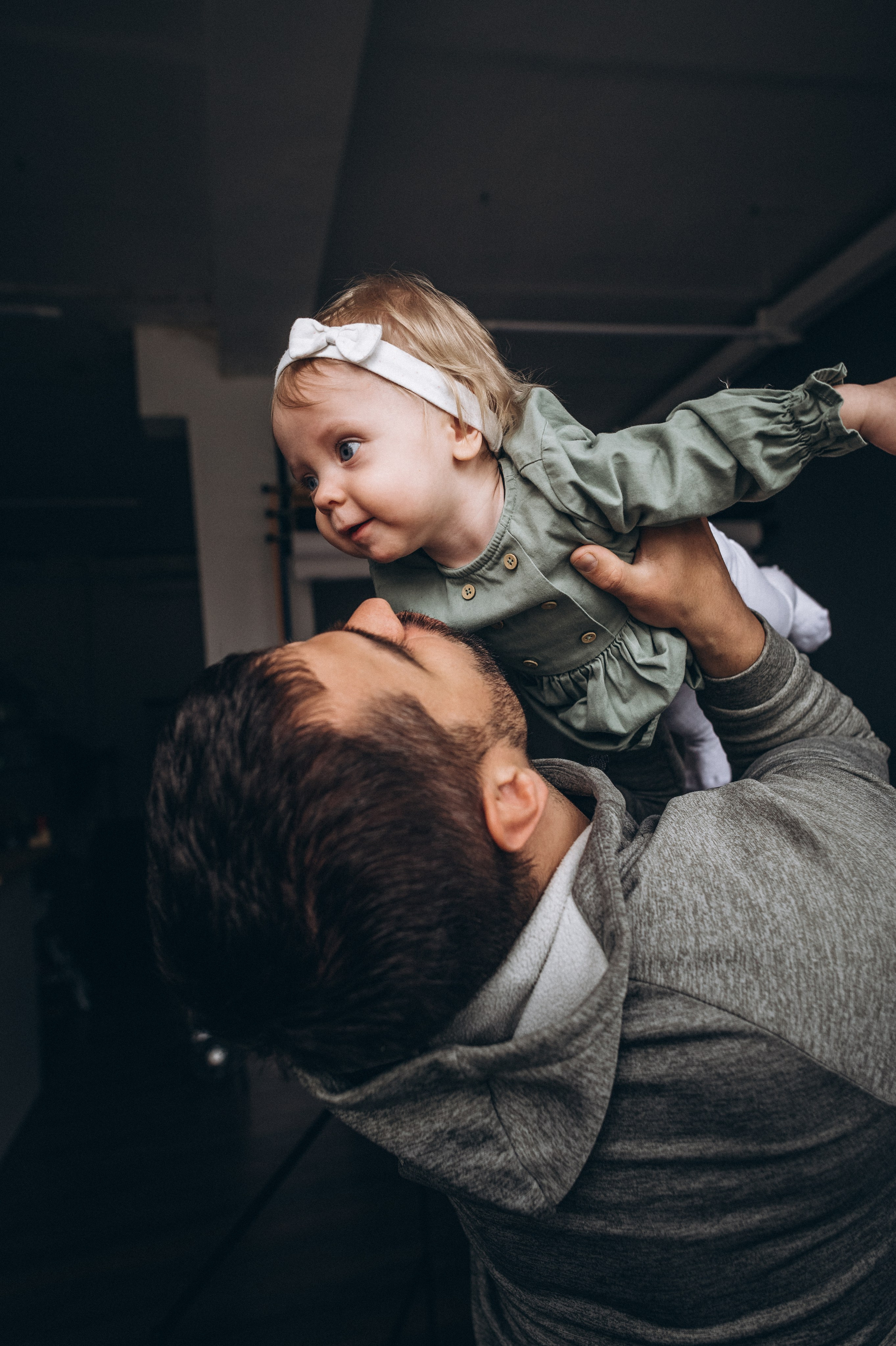 Папа поднимает дочку над головой во время студийной семейной съемки