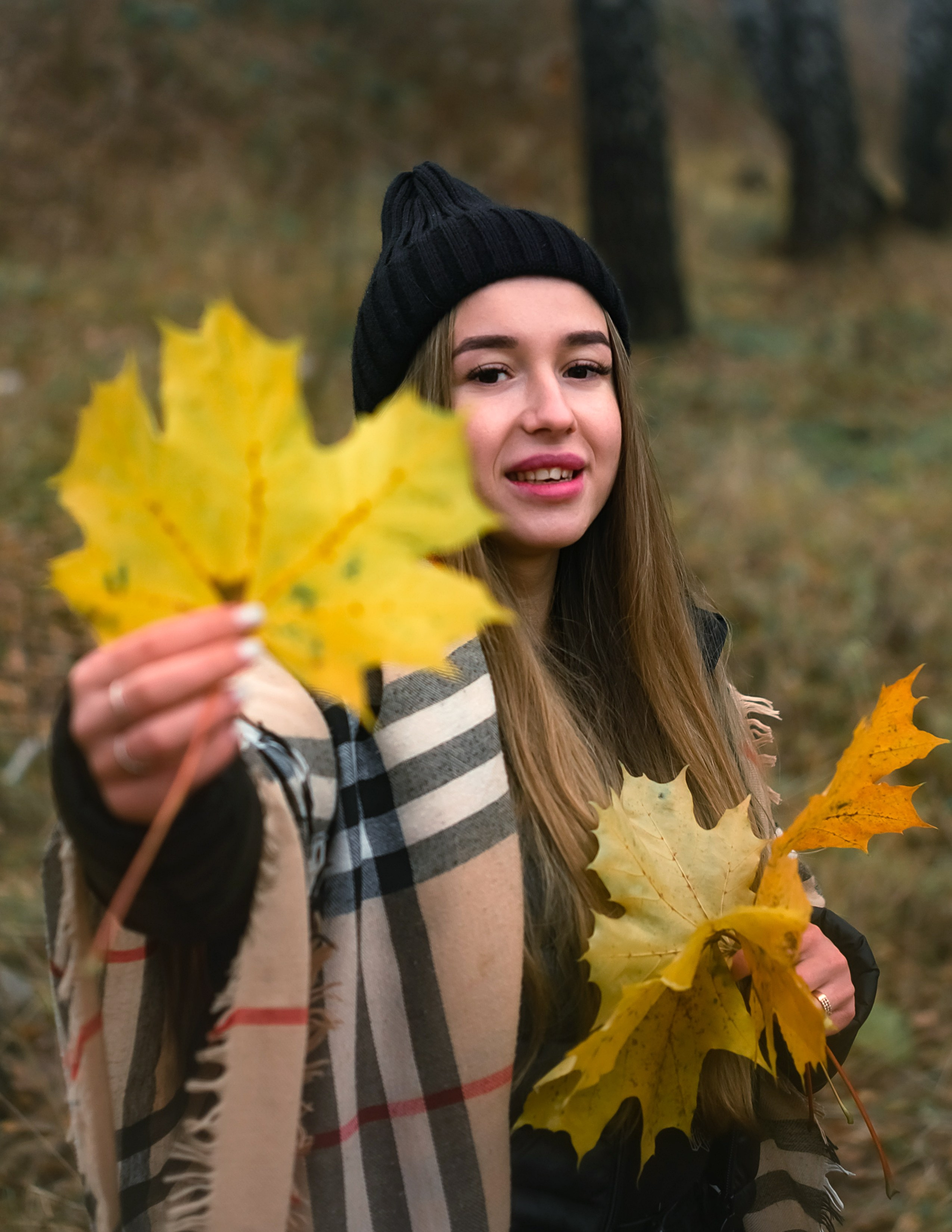 На фото портрет девушки осенним букетом из листьев.