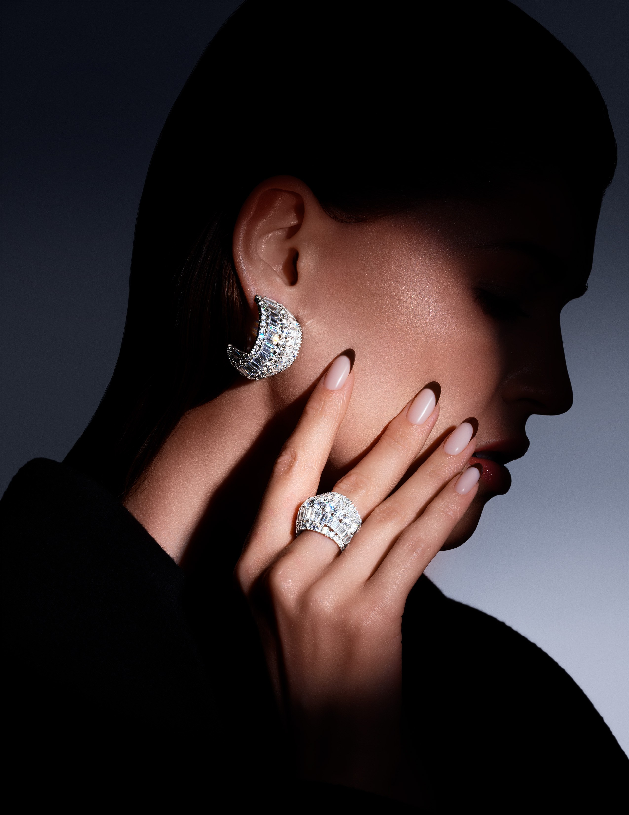 Sophisticated close-up of a model wearing Swarovski silver statement rings and earrings, styled for a luxury jewelry editorial.
