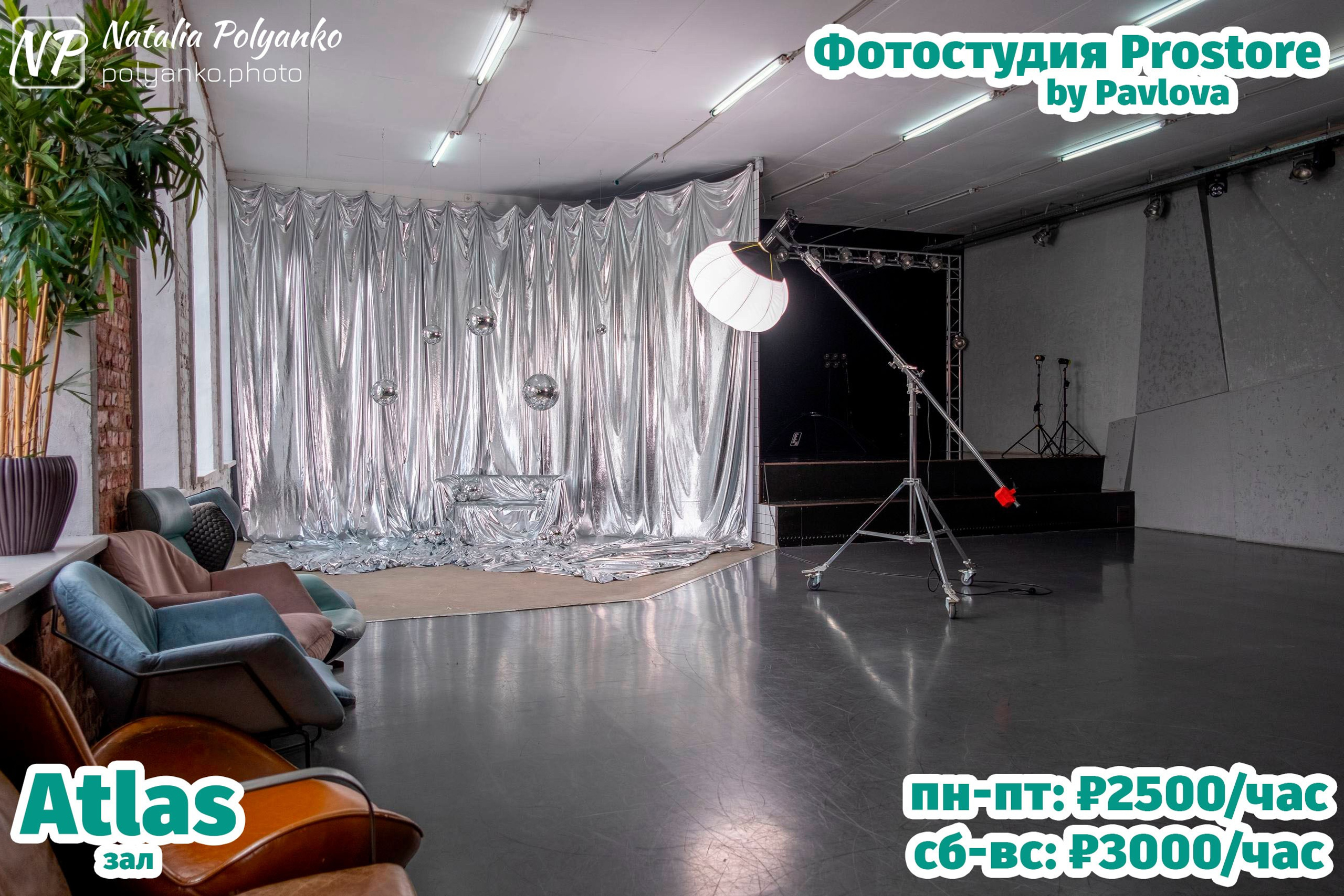 Зал с черной сценой, электрогитарой и профессиональным освещением. Современное пространство с подиумом и световыми приборами, расположенными по периметру сцены. На заднем плане — геометричная серая стена и одна черная гитара на стойке. В левом нижнем углу указано название зала - Atlas (Атлас), в правом верхнем — "Фотостудия by Pavlova", а внизу указана стоимость аренды: пн-пт 2500 руб/час, сб-вс 3000 руб/час.