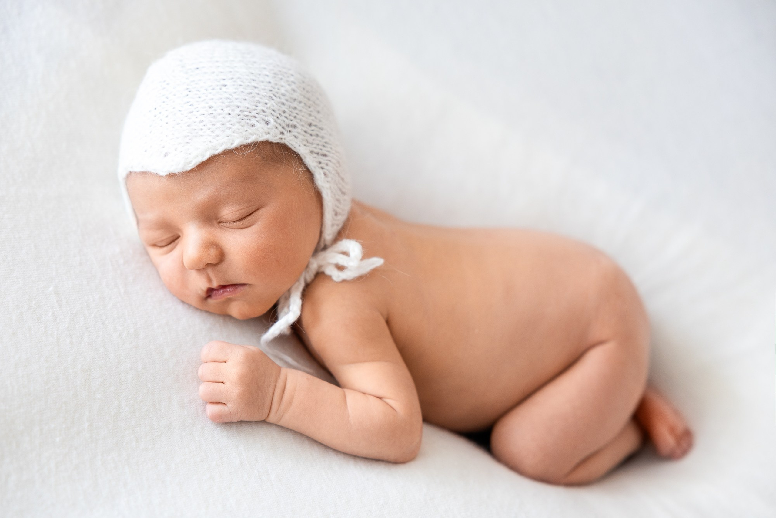 Ньюборн съемка голышом в шапочке на тканевом фоне.