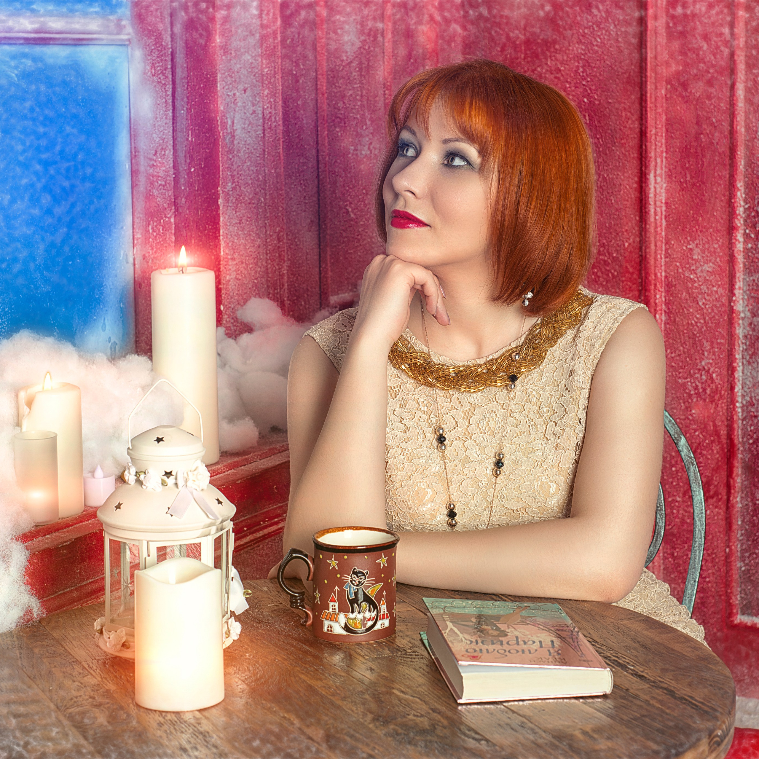 Рыжая девушка сидит в новогодней декорации у свечи